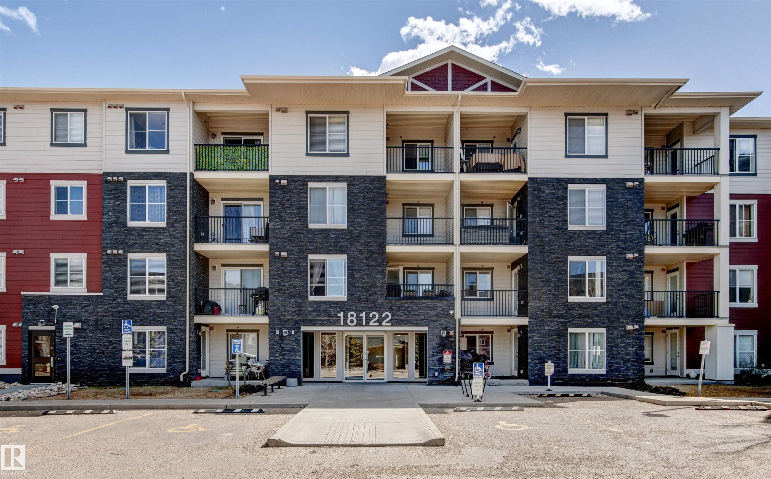 Multi-story facade featuring dark stacked stone accents and light-colored siding - #208 18122 77 St Nw, Edmonton, AB