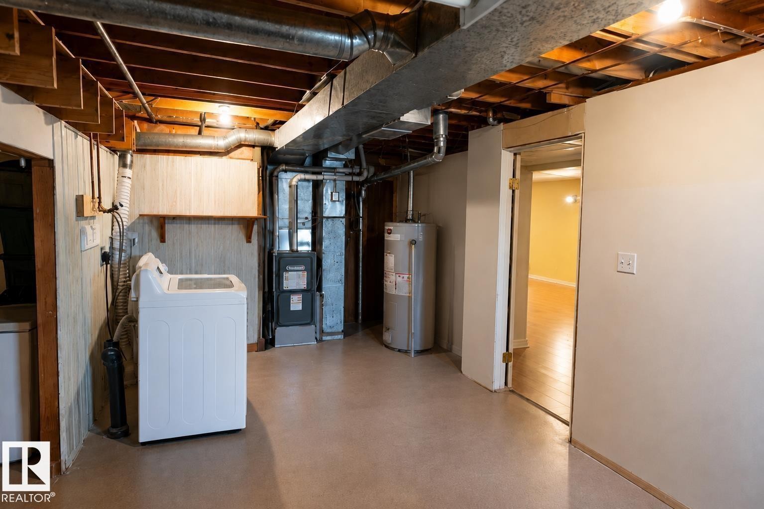 Unfinished basement area with exposed ceiling joists and ductwork, featuring a water heater and furnace - 10439 36A Ave Nw, Edmonton, AB