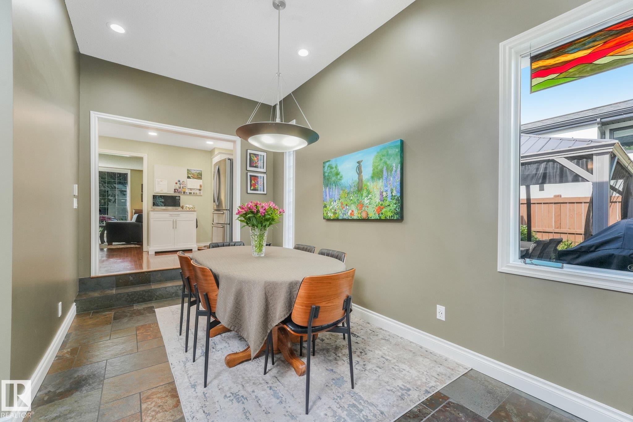 Dining area featuring vaulted ceilings, recessed lighting, a modern pendant light fixture, and Brazilian stone tile flooring with in-floor heating. - 10531 137 Street Nw, Edmonton, AB