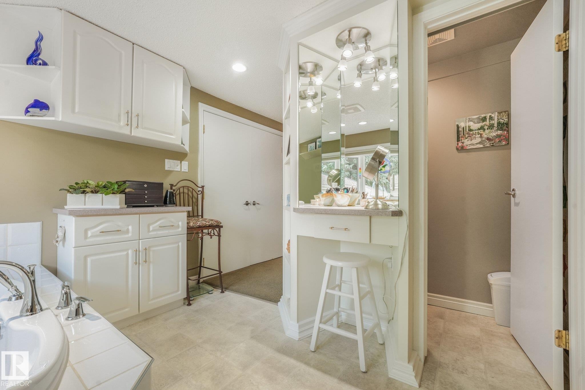 White cabinetry with recessed panel doors, built-in vanity with mirror and task lighting, recessed overhead lighting, and a built-in soaker tub - 10531 137 Street Nw, Edmonton, AB