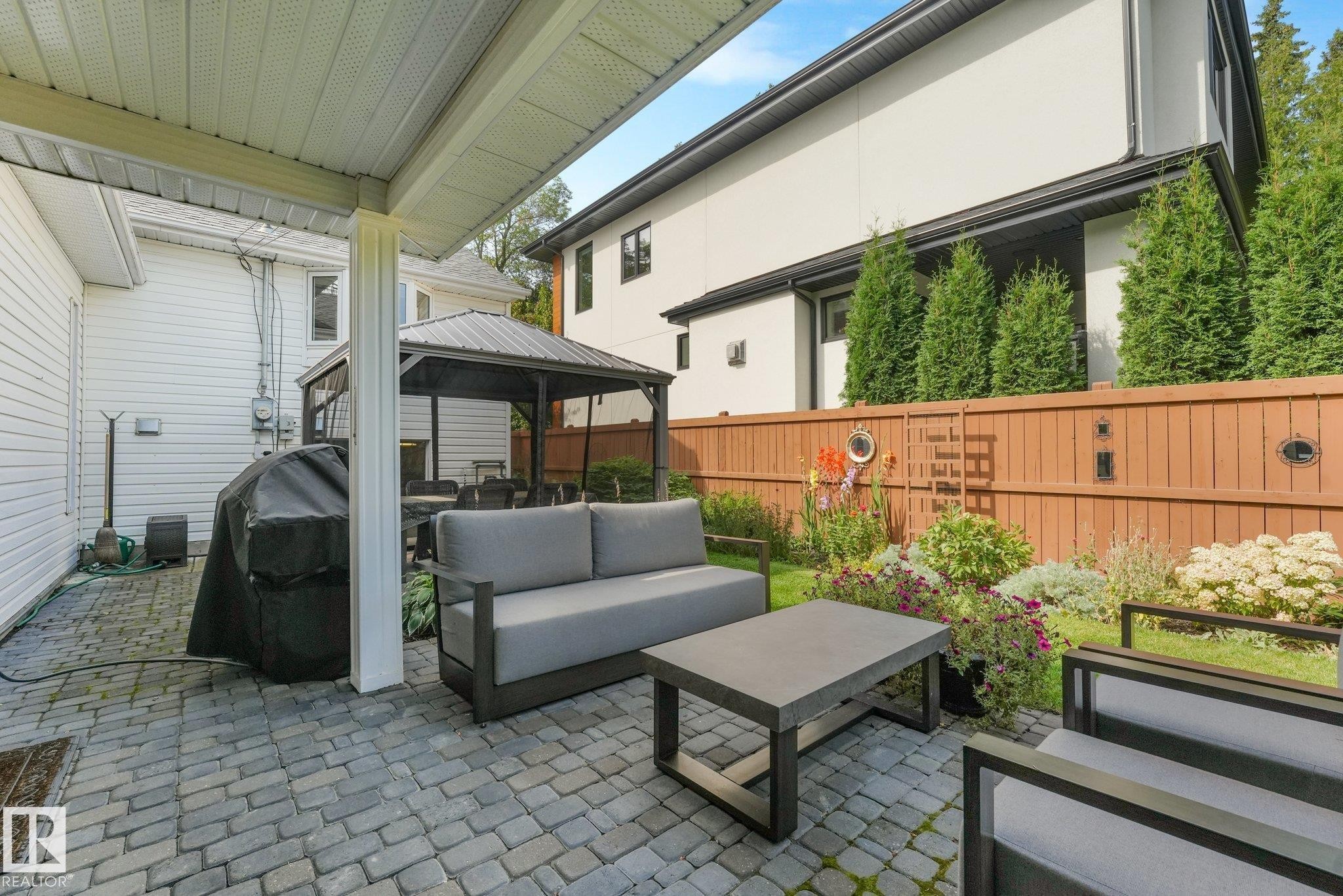 Paved patio area, covered outdoor space, a gazebo, landscaped garden beds, and a wood fence with planted evergreens - 10531 137 Street Nw, Edmonton, AB