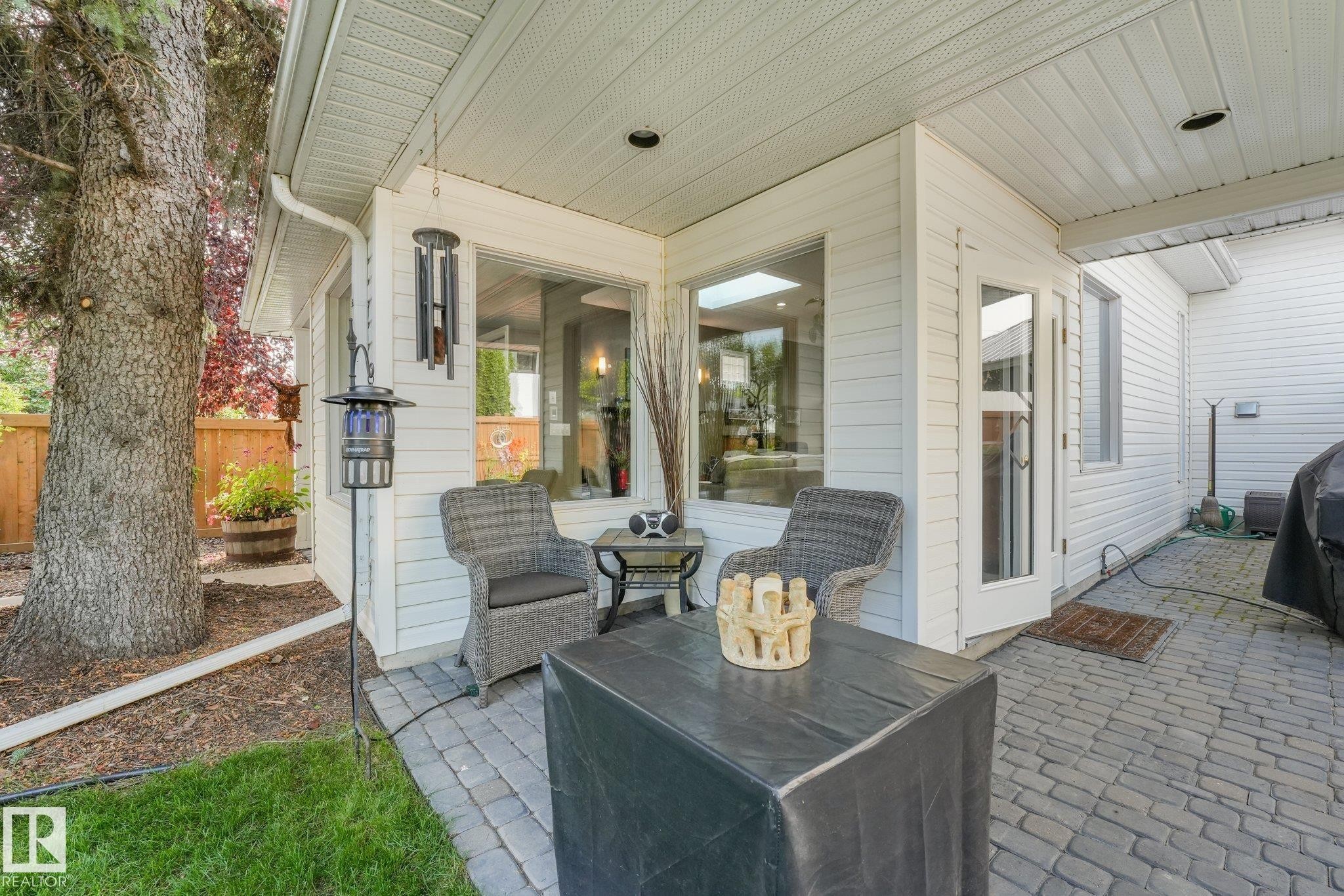 Outdoor covered patio featuring paver flooring, white siding, and a wooden fence - 10531 137 Street Nw, Edmonton, AB