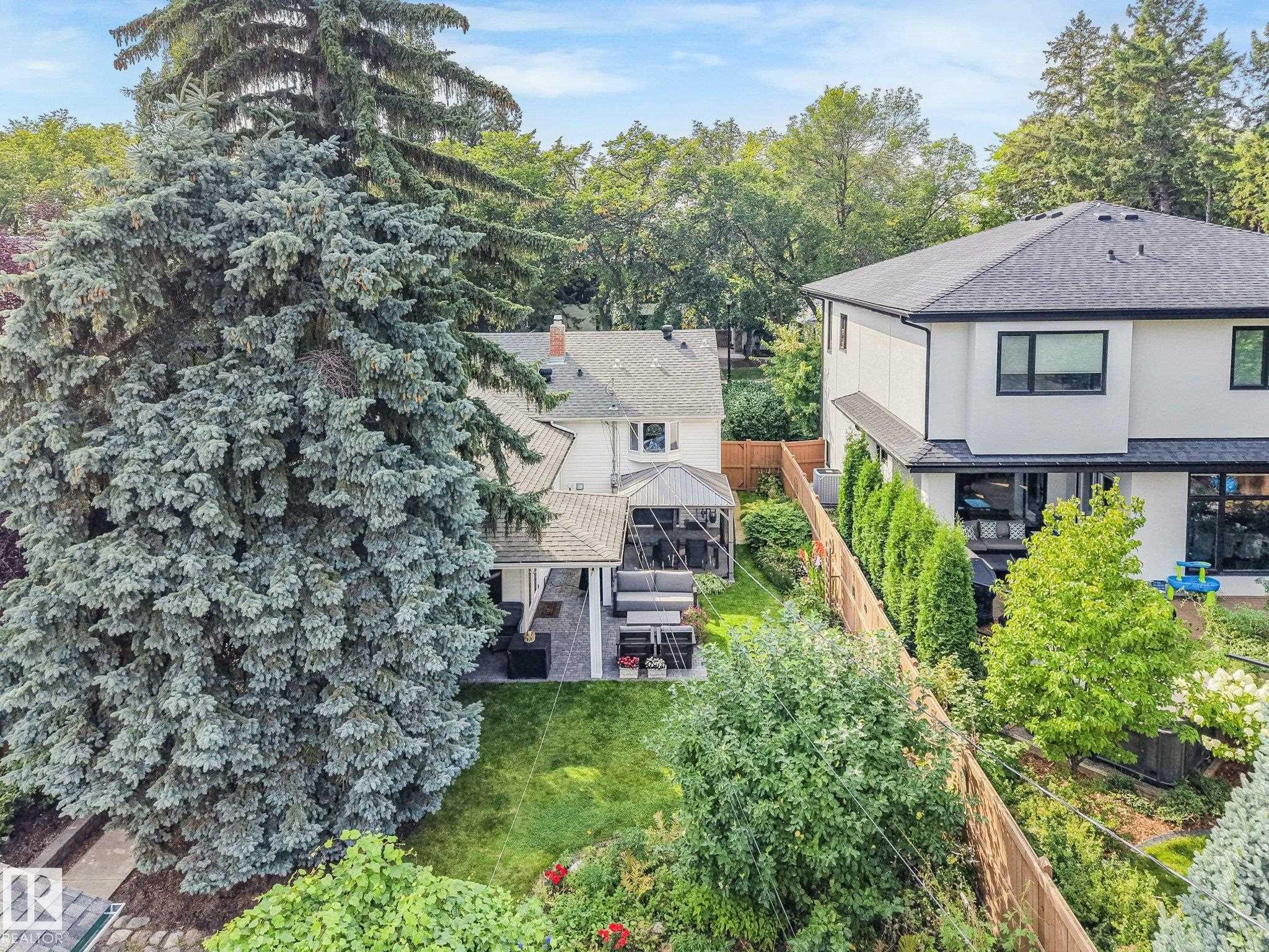 Expansive backyard featuring a paver patio with a gazebo, mature trees, and a manicured lawn - 10531 137 Street Nw, Edmonton, AB