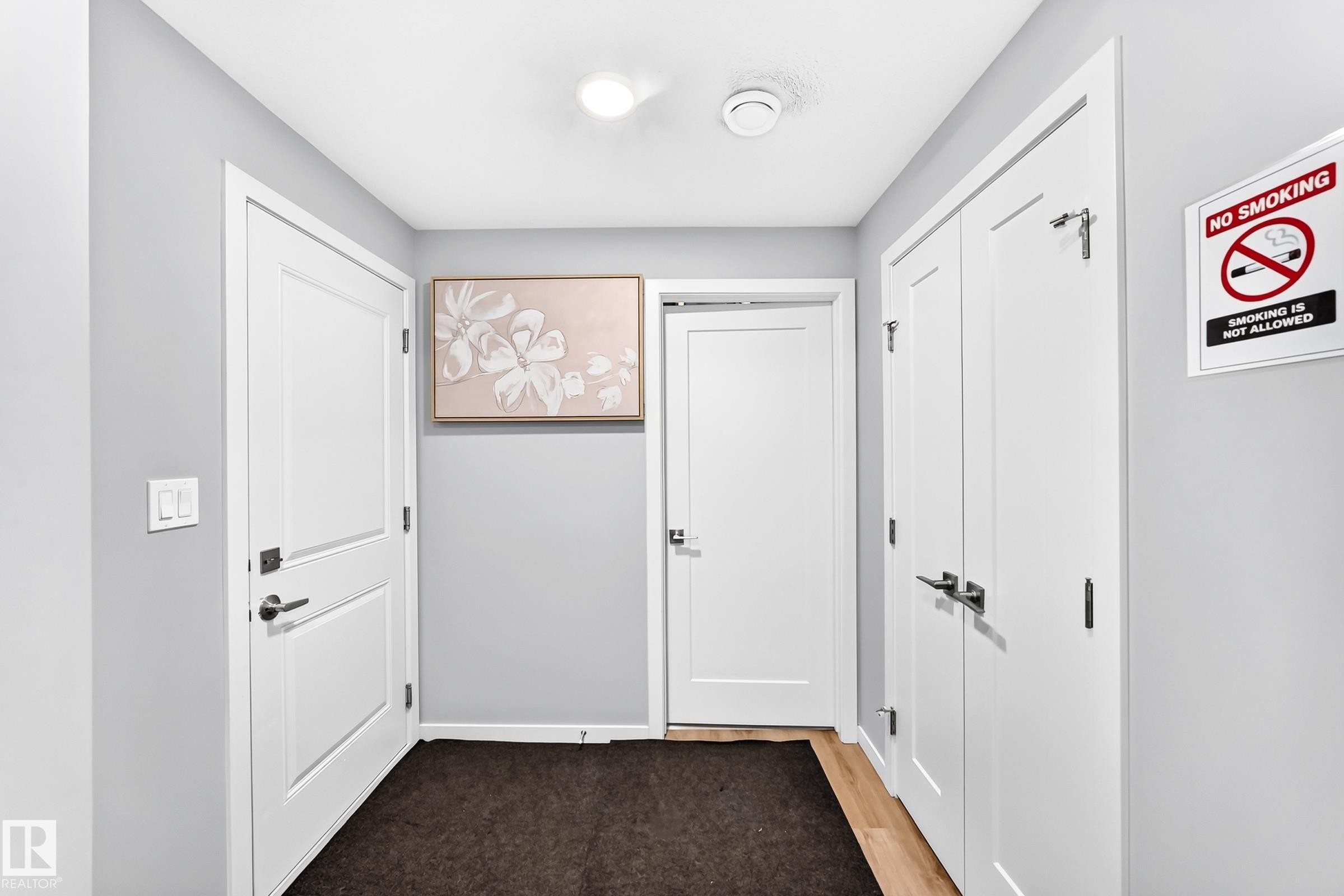 Hardwood-style flooring in the entryway with white paneled doors and modern hardware - 479 39 St Sw, Edmonton, AB