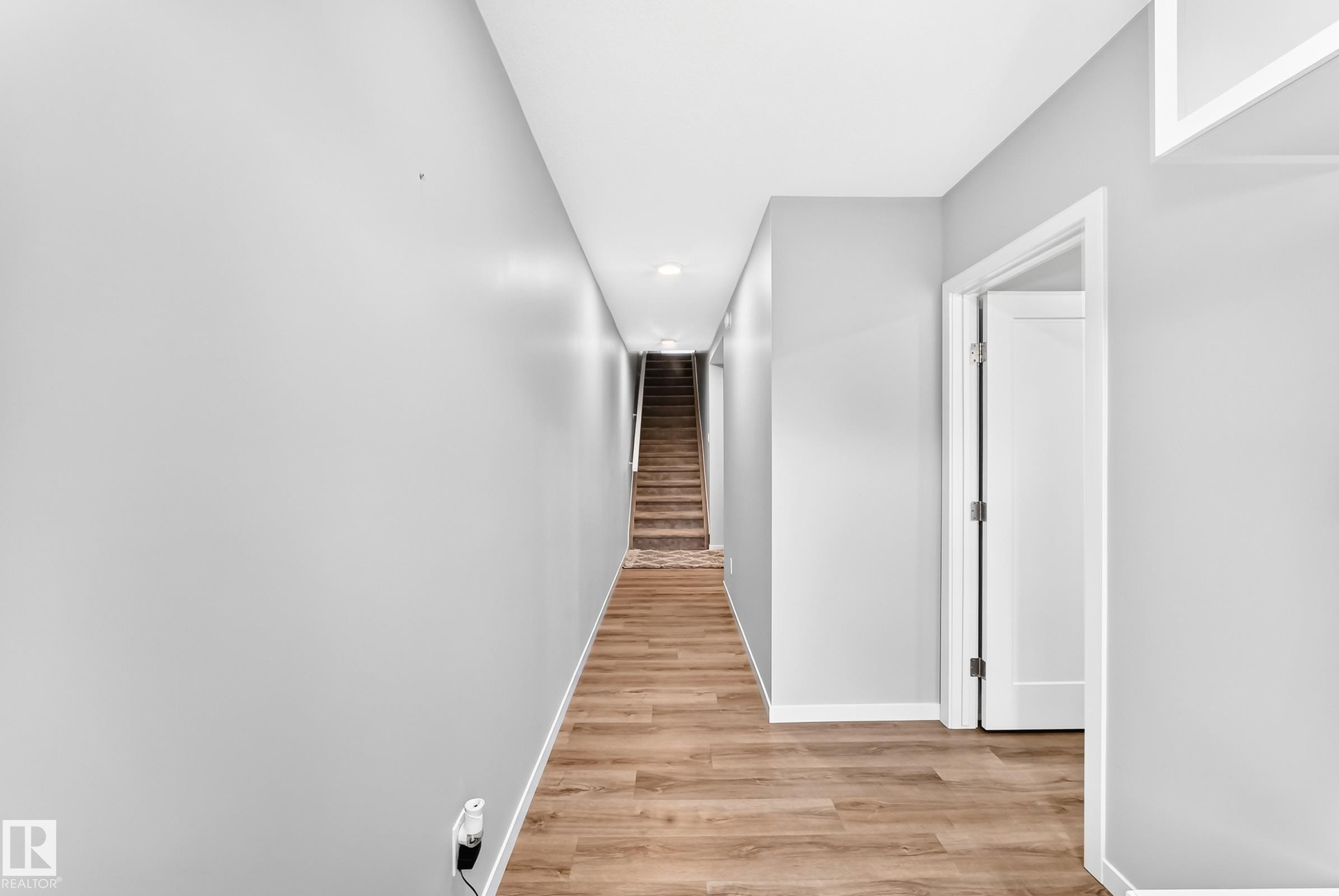 Hallway with wood-finish flooring, recessed lighting, and a solid interior door - 479 39 St Sw, Edmonton, AB