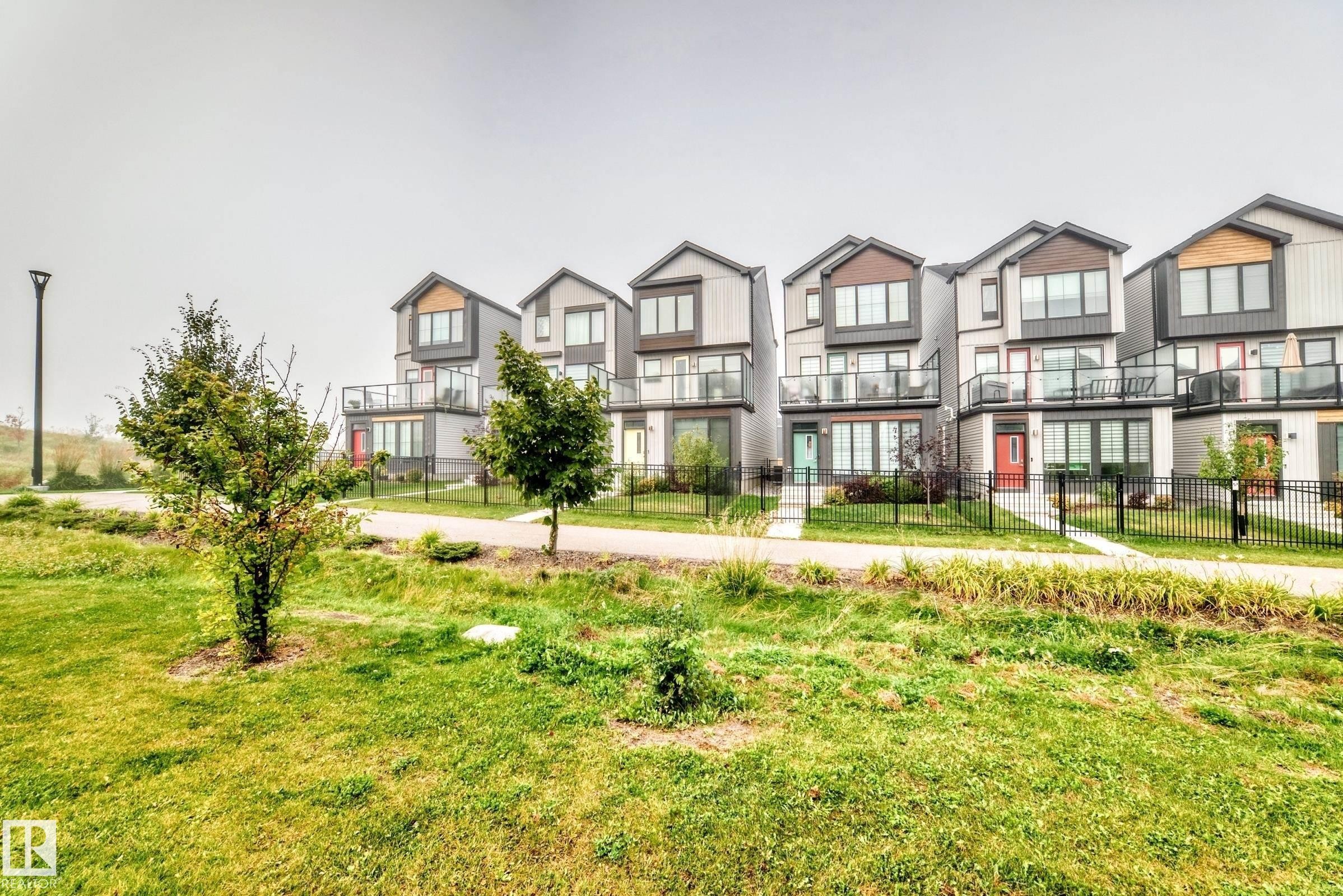 Contemporary multi-story facades with varied cladding, private balconies featuring glass railings, and individual front entrances - 479 39 St Sw, Edmonton, AB