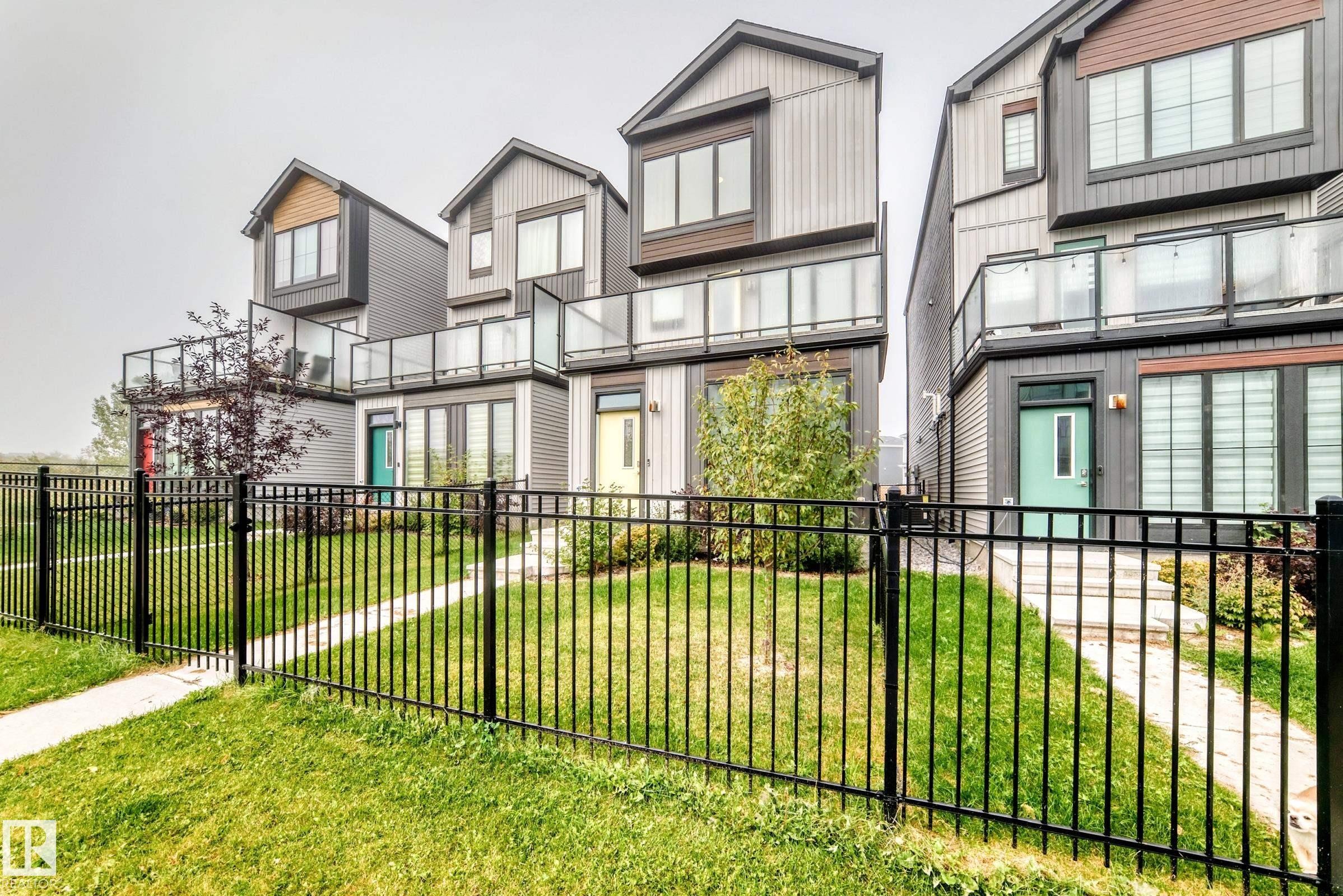 Modern facades featuring horizontal and vertical siding, upper-level balconies with glass railings, and ground-level patios with privacy screens - 479 39 St Sw, Edmonton, AB