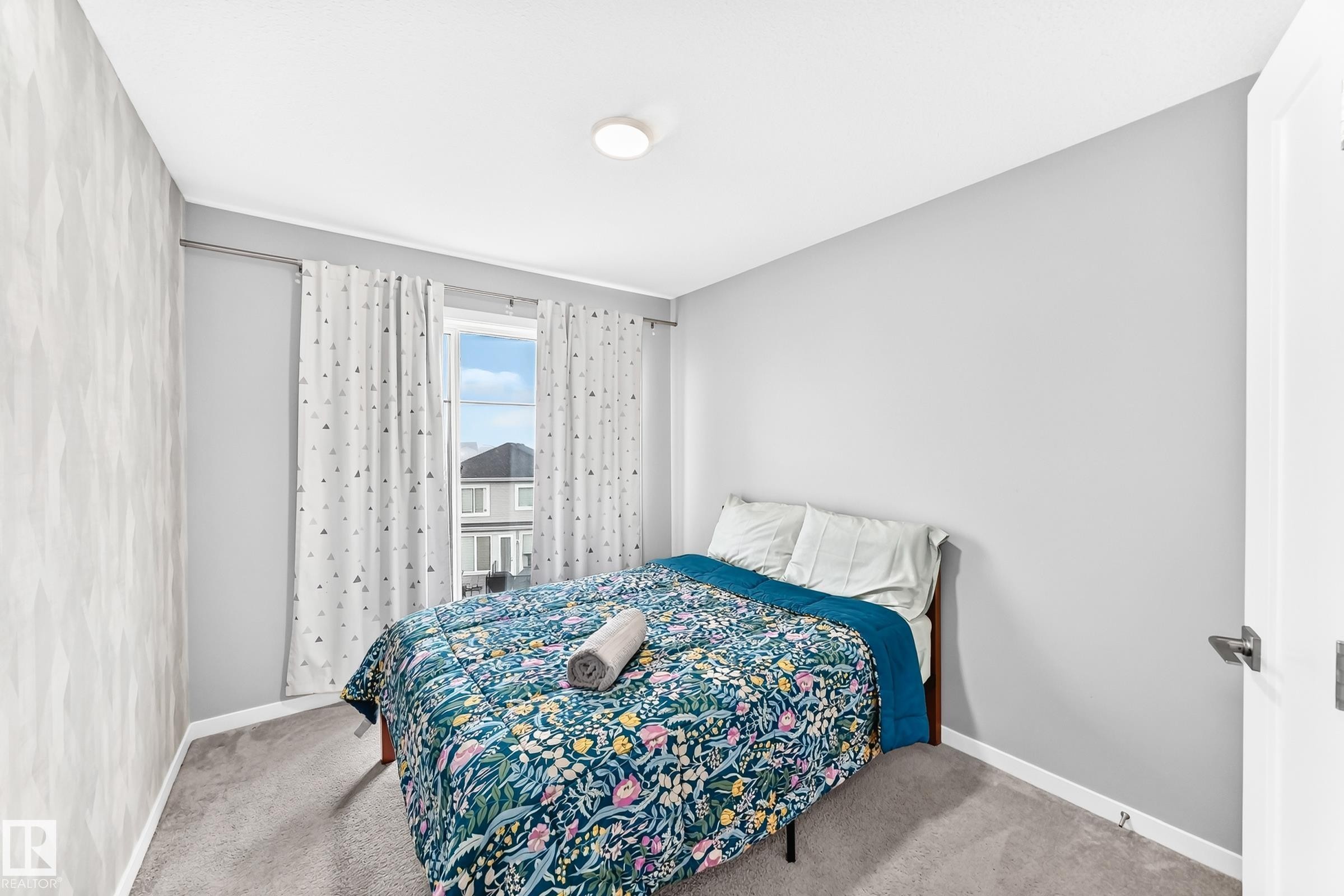 Carpeted flooring, window with drapes, flush mount ceiling light, and textured accent wall - 479 39 St Sw, Edmonton, AB