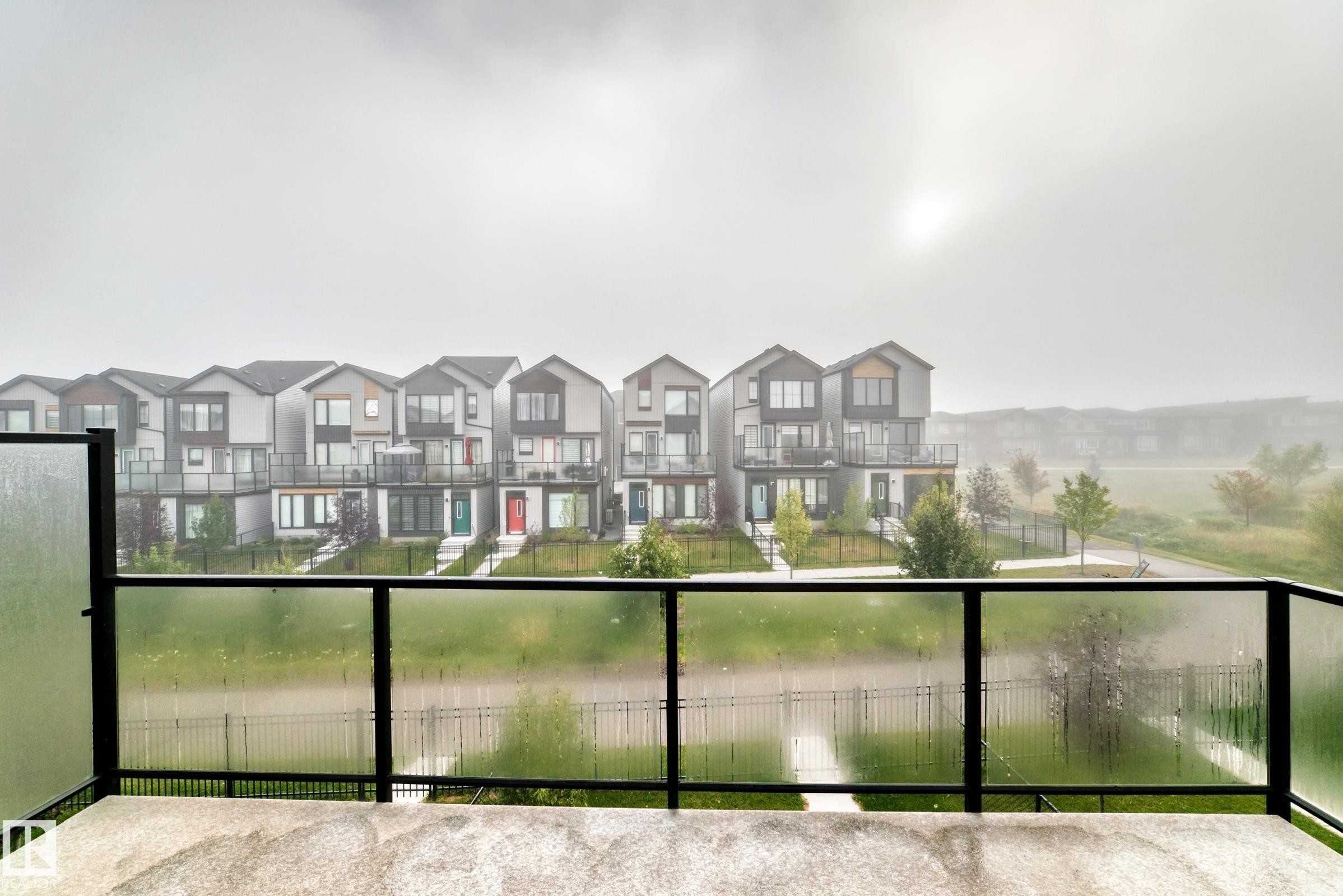 Concrete balcony with a black metal and frosted glass railing - 479 39 St Sw, Edmonton, AB