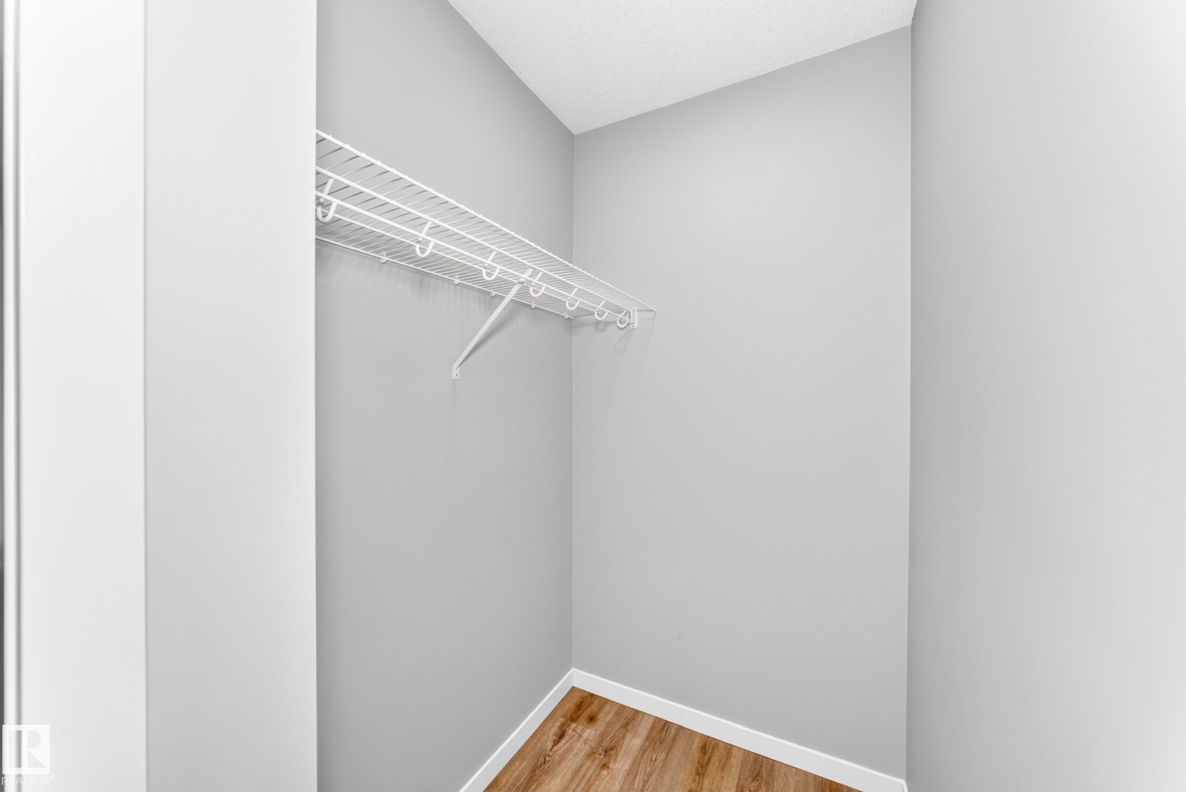 Wire shelving system with a hanging rod and wood-finish flooring - 479 39 St Sw, Edmonton, AB