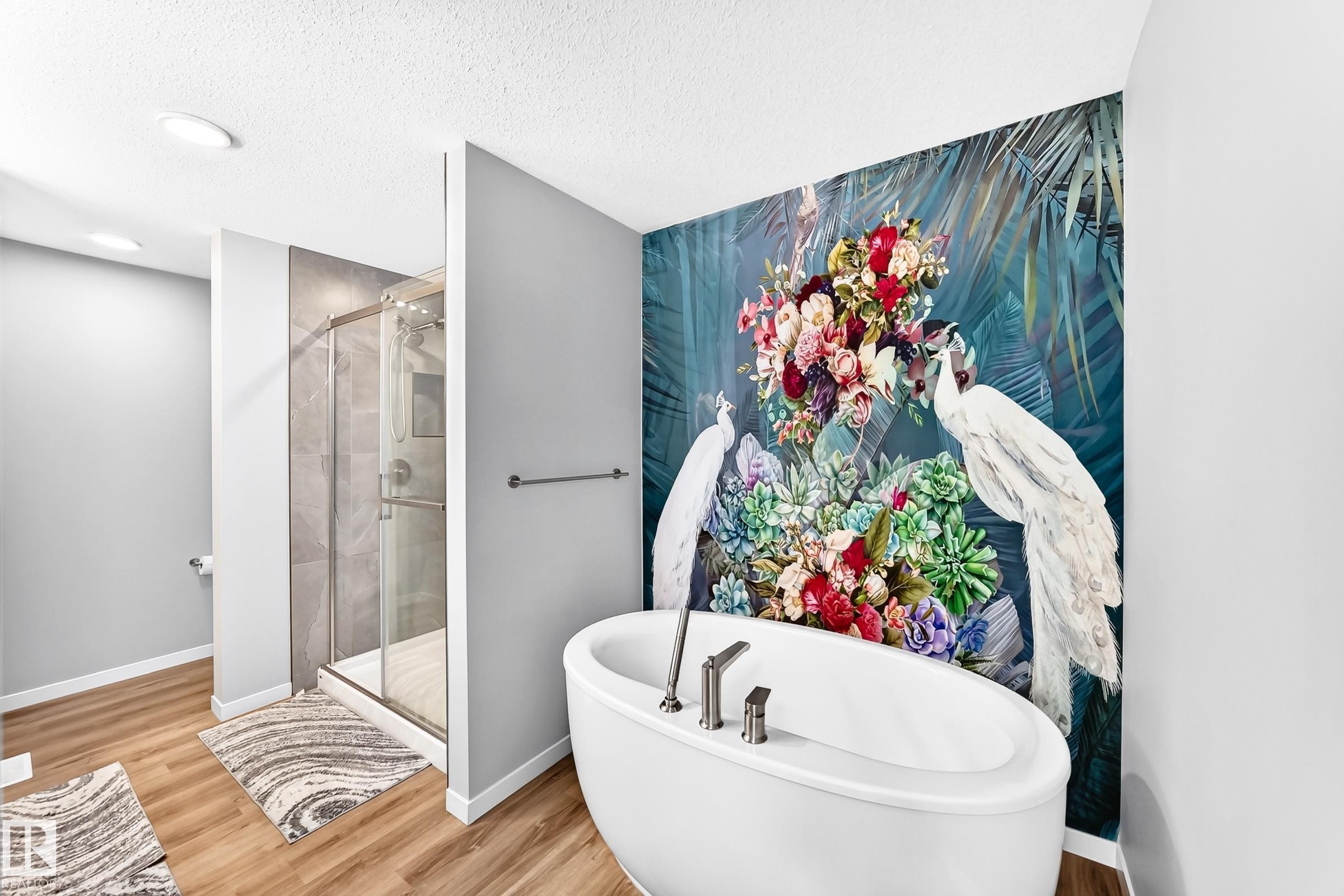 Freestanding soaking tub with floor-mounted faucet, glass-enclosed shower, wood-finish flooring, and recessed ceiling lighting - 479 39 St Sw, Edmonton, AB