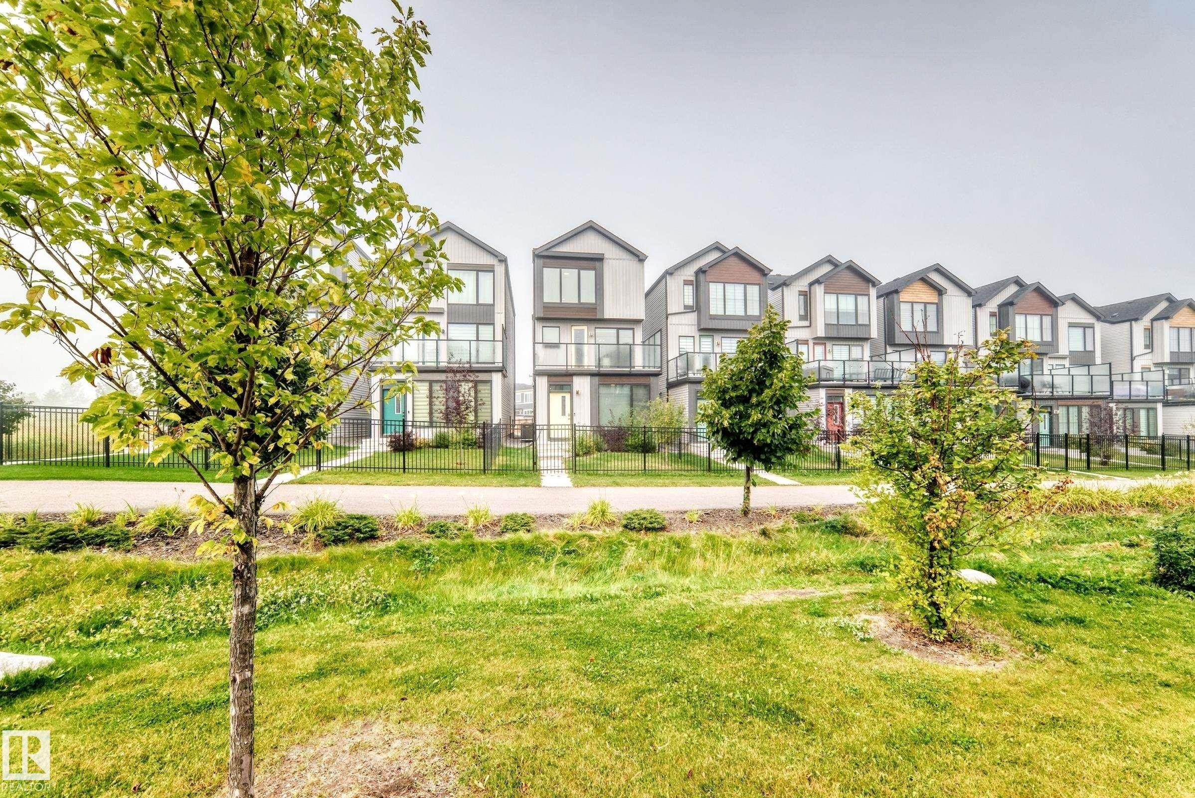 Modern townhouse exteriors featuring varied rooflines, glass balcony railings, and individual front walkways - 479 39 St Sw, Edmonton, AB