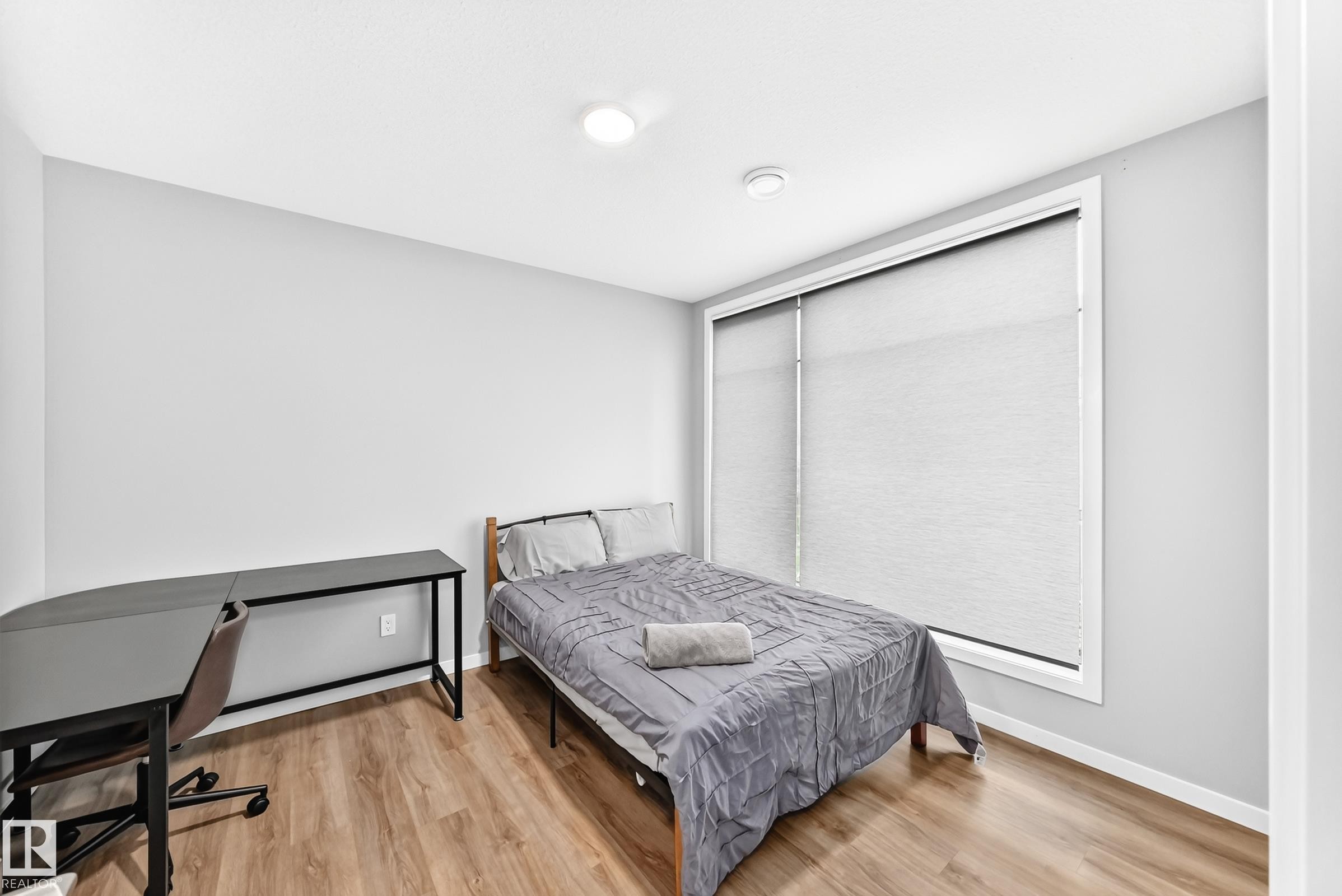 Wood-finish flooring with neutral wall tones and a window with roller shades - 479 39 St Sw, Edmonton, AB