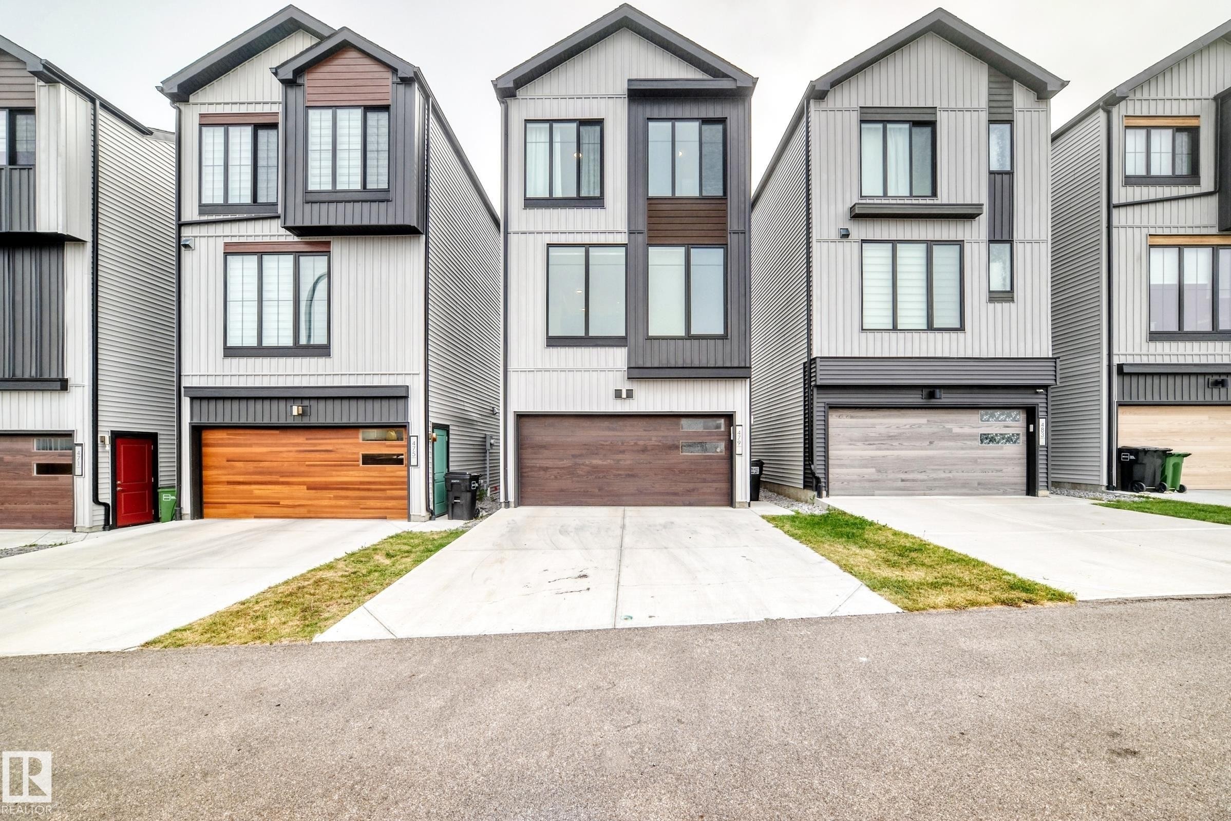Contemporary exterior with vertical siding, dark trim accents, multiple windows, and a wood-finish garage door - 479 39 St Sw, Edmonton, AB