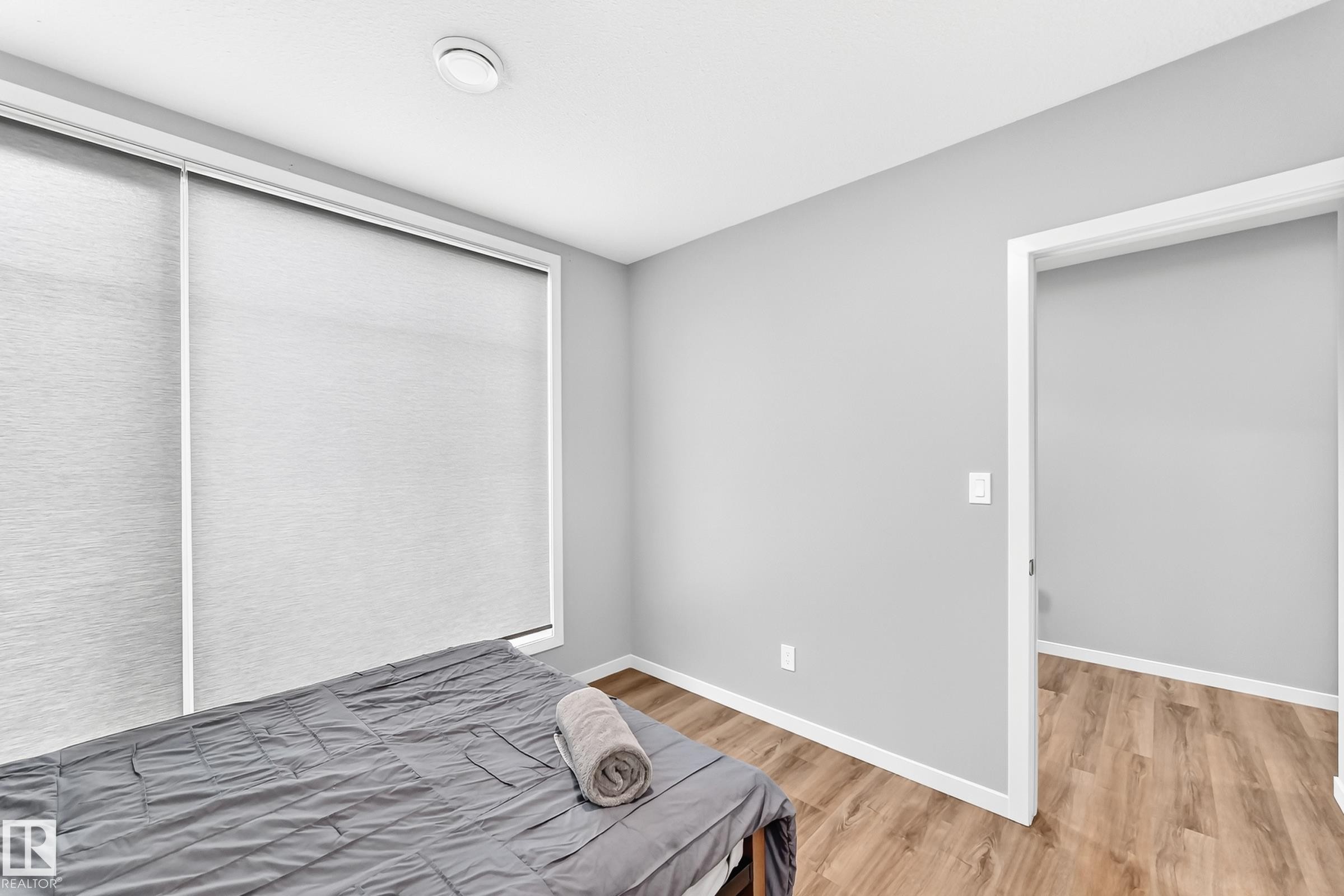 Neutral wall paint, window with roller shades, wood-finish flooring, white trim, recessed ceiling light - 479 39 St Sw, Edmonton, AB
