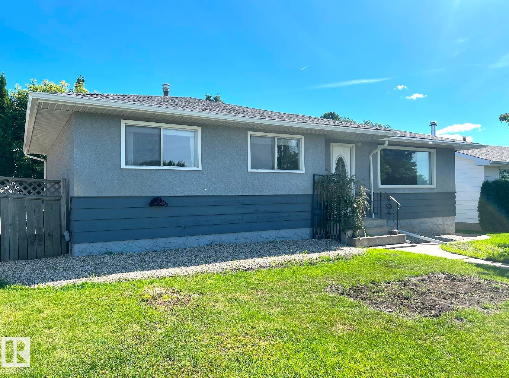 Bungalow exterior with a gray stucco finish and a contrasting dark gray lower facade - 15003 81 Street Nw, Edmonton, AB