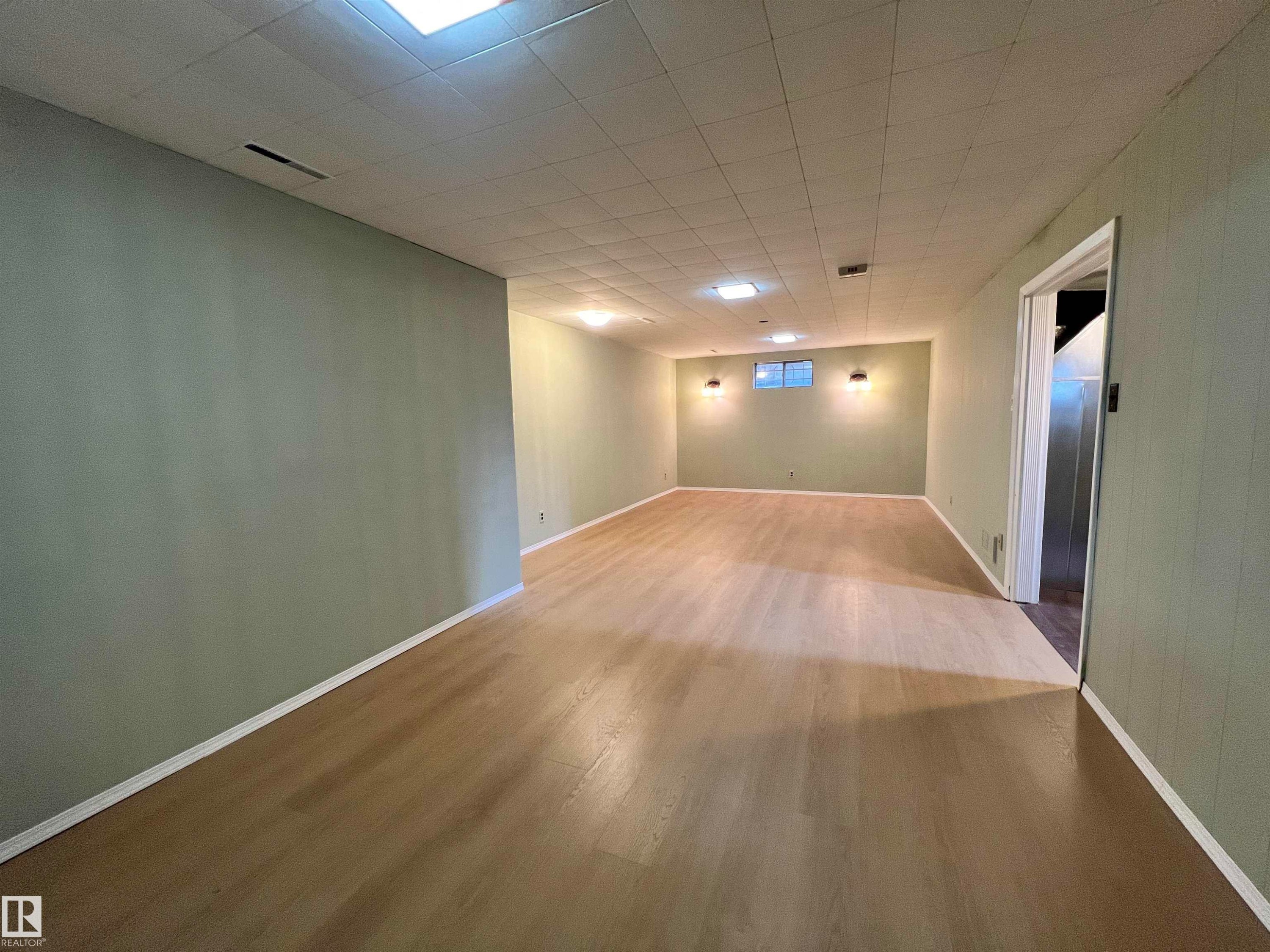 Expansive room featuring light wood-finish flooring, recessed lighting, and wall-mounted sconces - 15003 81 Street Nw, Edmonton, AB