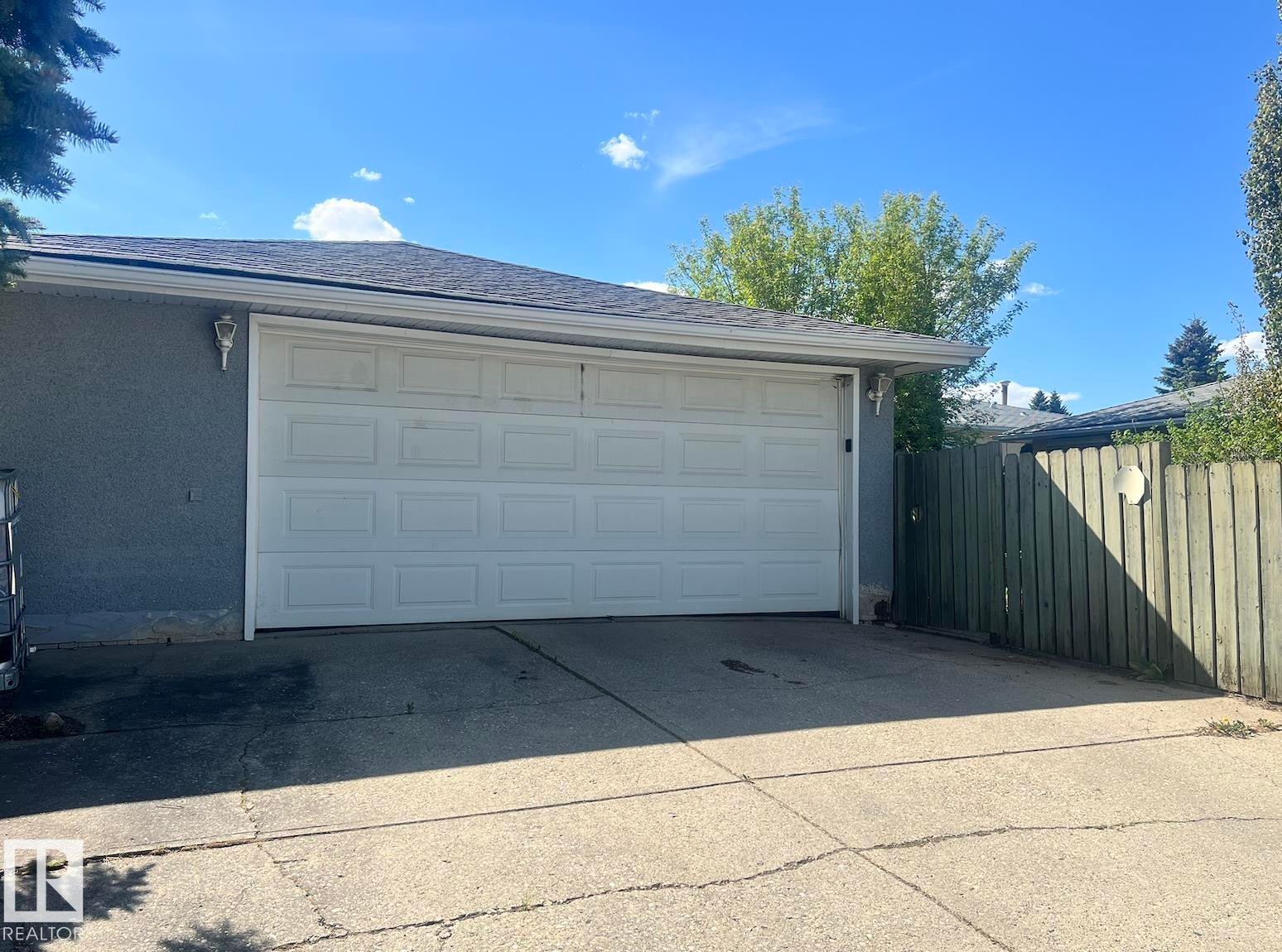 Attached single-car garage with a panel door, stucco exterior, and asphalt shingle roof - 15003 81 Street Nw, Edmonton, AB