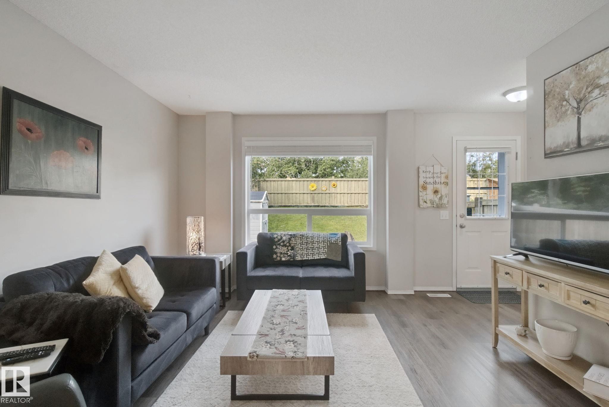Hardwood-finish flooring, light neutral wall tones, rear yard access, and a large window with natural light - 15618 141 Street Nw, Edmonton, AB
