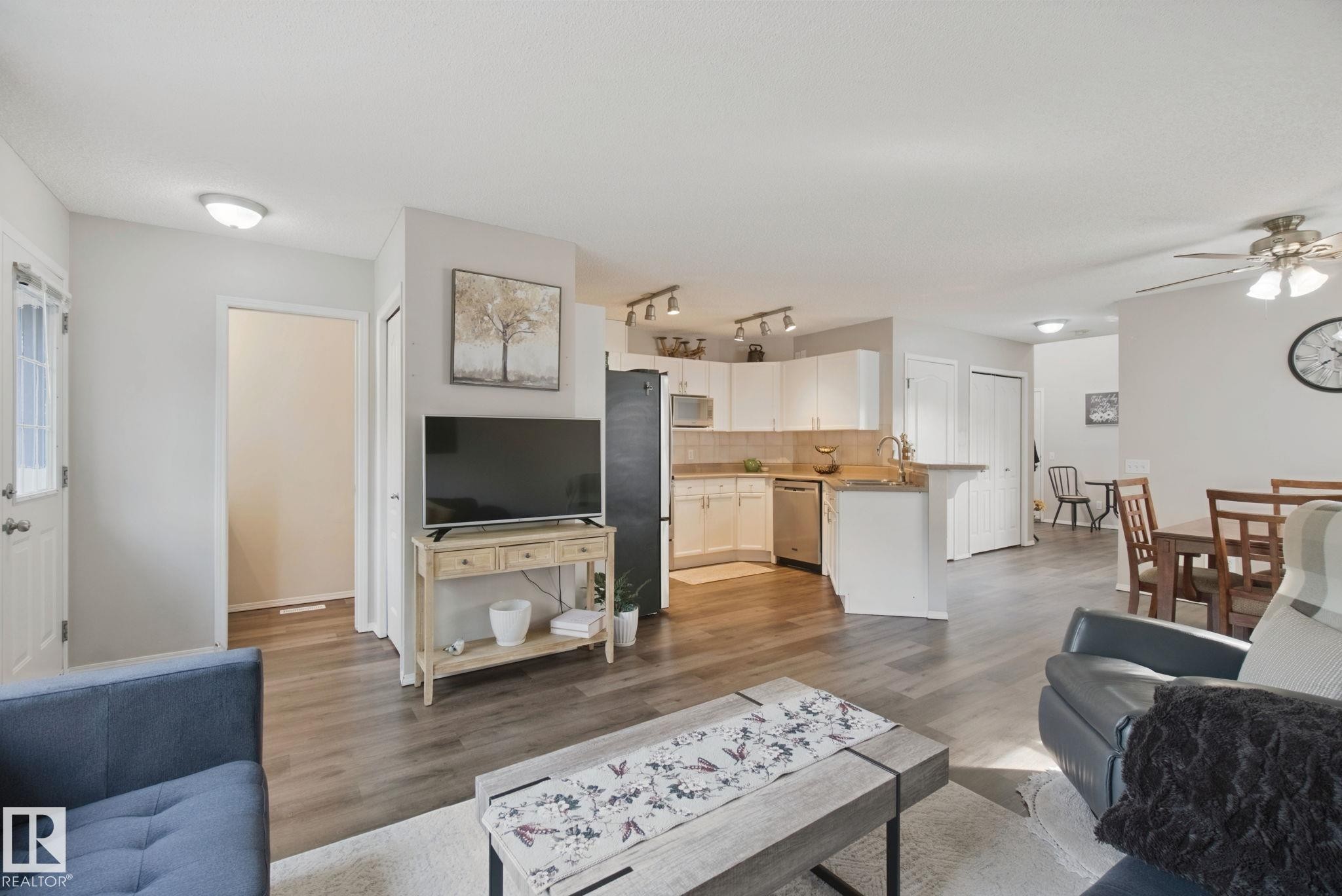 Wood-finish flooring throughout, white kitchen cabinetry, stainless steel appliances, and ceiling fan - 15618 141 Street Nw, Edmonton, AB
