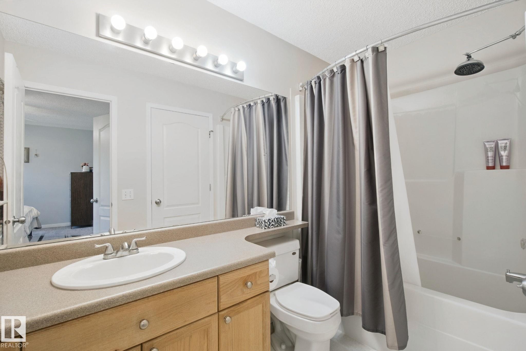 Spa-inspired bathroom featuring a wood-finish vanity with dual storage drawers, white porcelain sink, and quartz countertop - 15618 141 Street Nw, Edmonton, AB