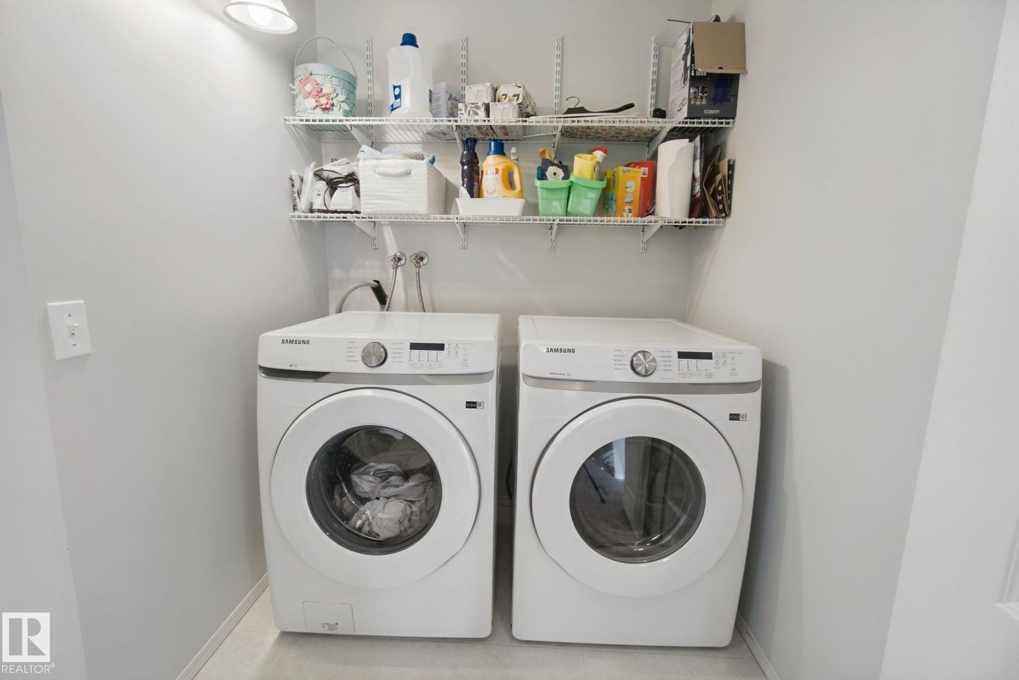 Two front-loading appliances, wall-mounted wire shelving, and overhead illumination - 15618 141 Street Nw, Edmonton, AB