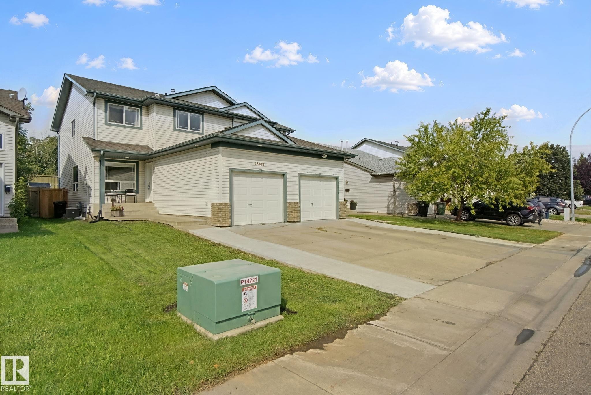 Two-story residence featuring light-colored siding, a two-car garage with white doors, and a concrete driveway - 15618 141 Street Nw, Edmonton, AB