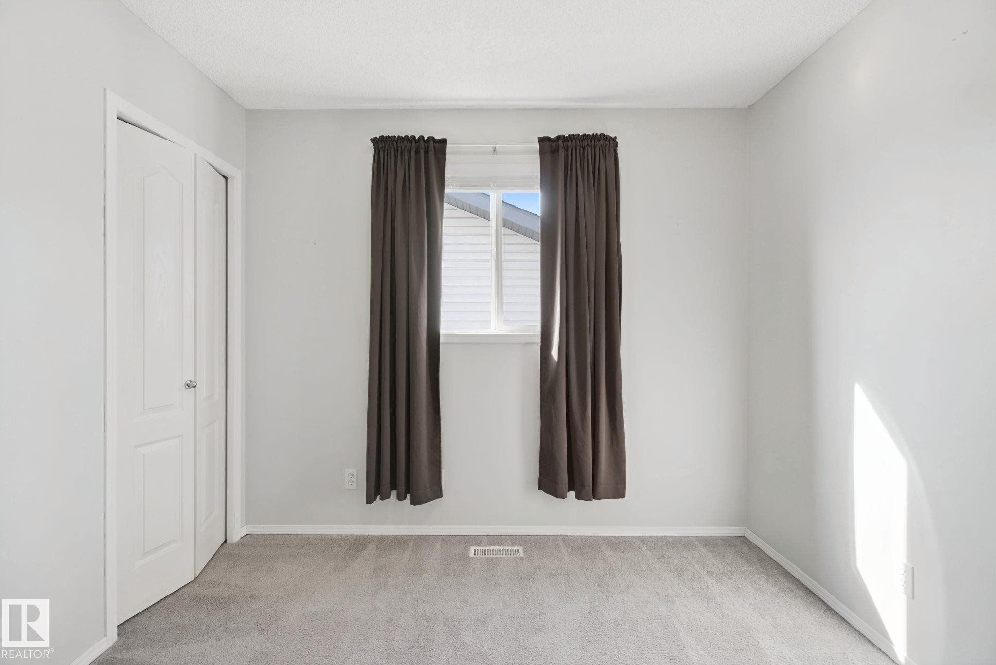 Recessed window, neutral wall paint, light-toned carpeting, and bi-fold closet doors - 15618 141 Street Nw, Edmonton, AB