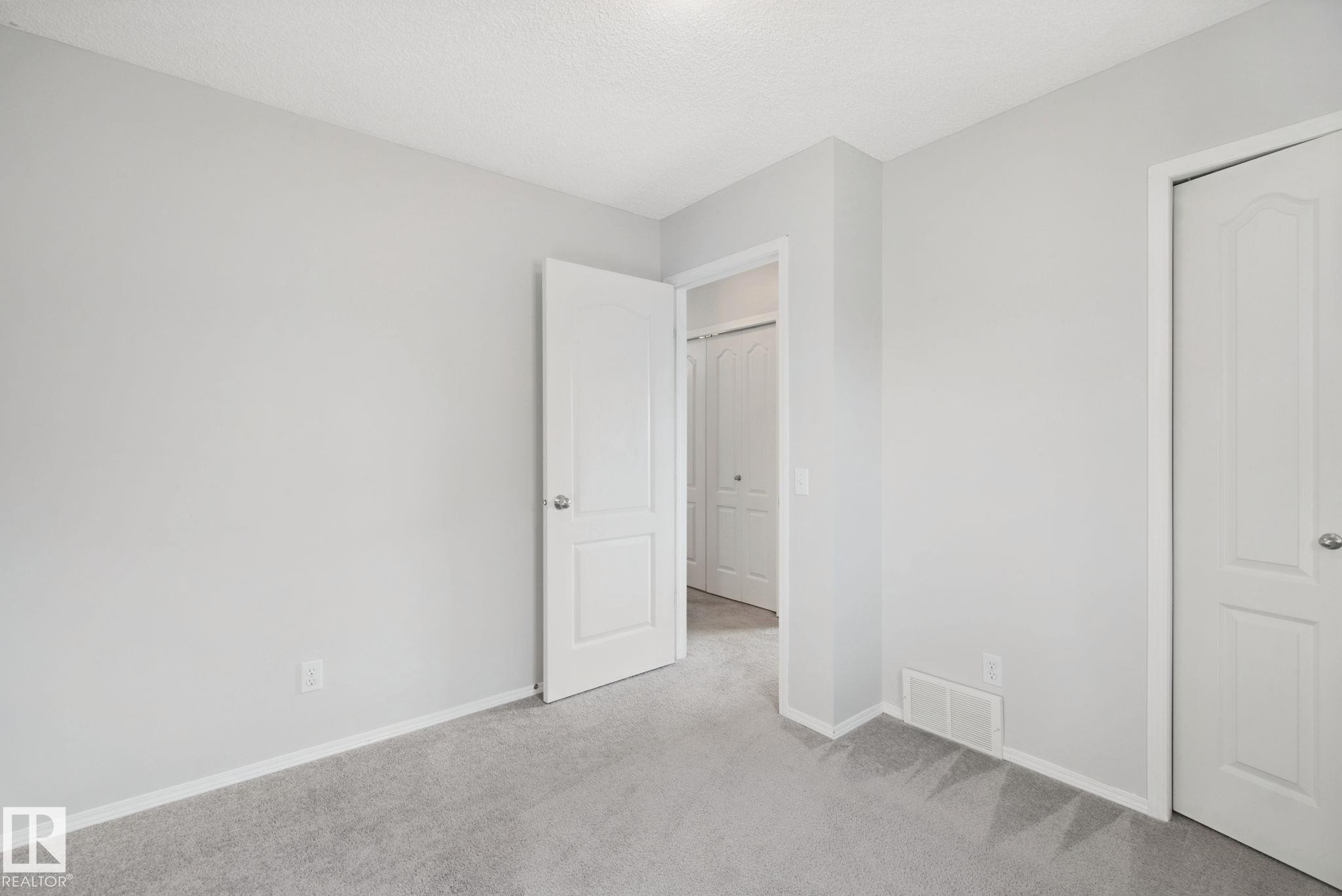 Plush carpeting, light-toned wall finishes, crisp white trim, and a white interior door - 15618 141 Street Nw, Edmonton, AB