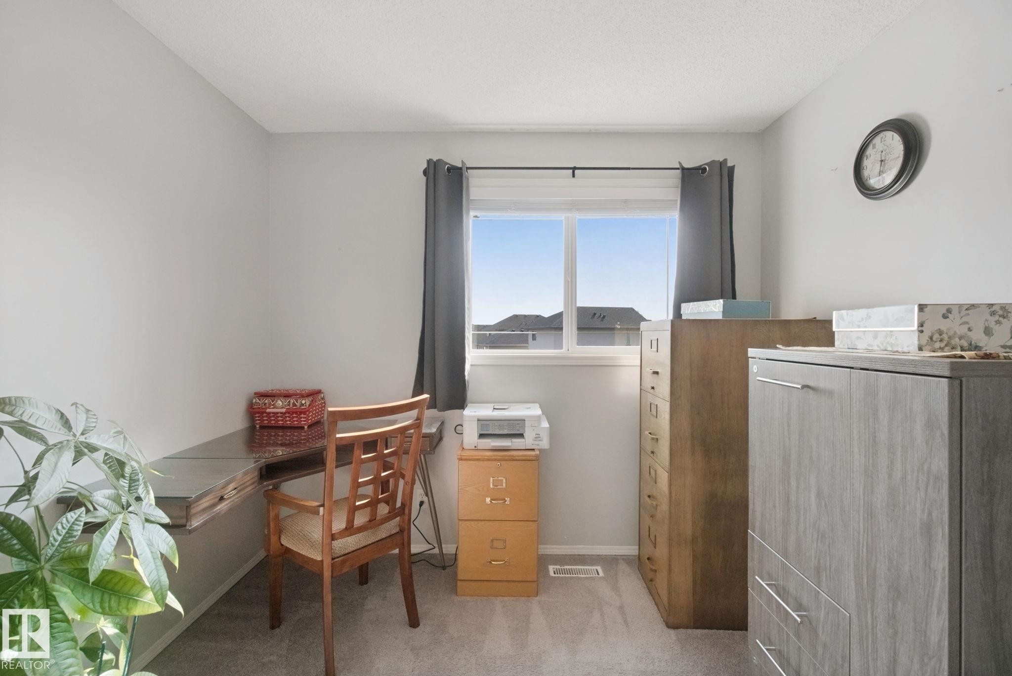 Light gray wall paint, window with white trim, gray carpet flooring, and a ceiling-mounted light fixture - 15618 141 Street Nw, Edmonton, AB