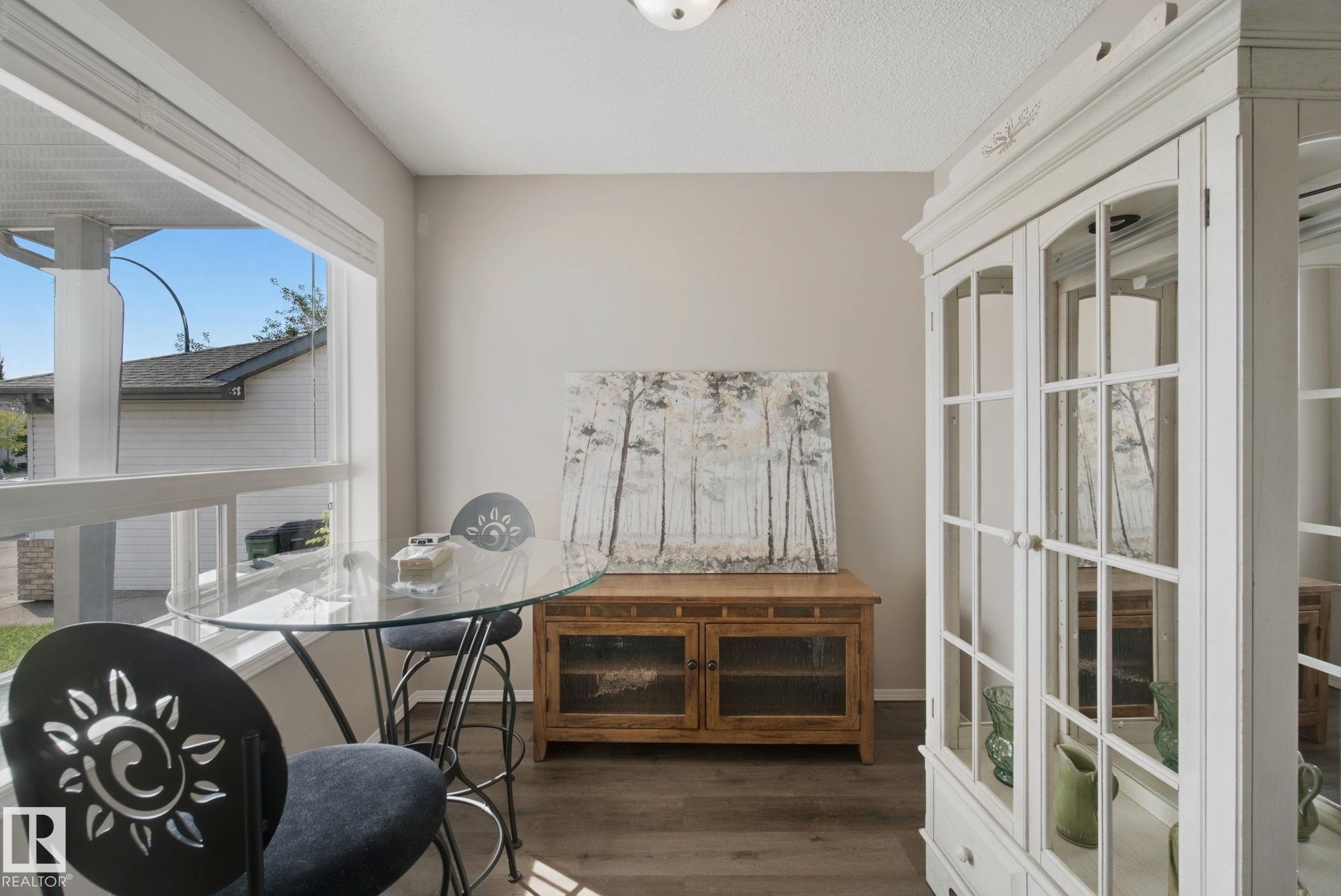 Wood-finish flooring throughout, large window for natural light, and a built-in display cabinet with glass panels - 15618 141 Street Nw, Edmonton, AB