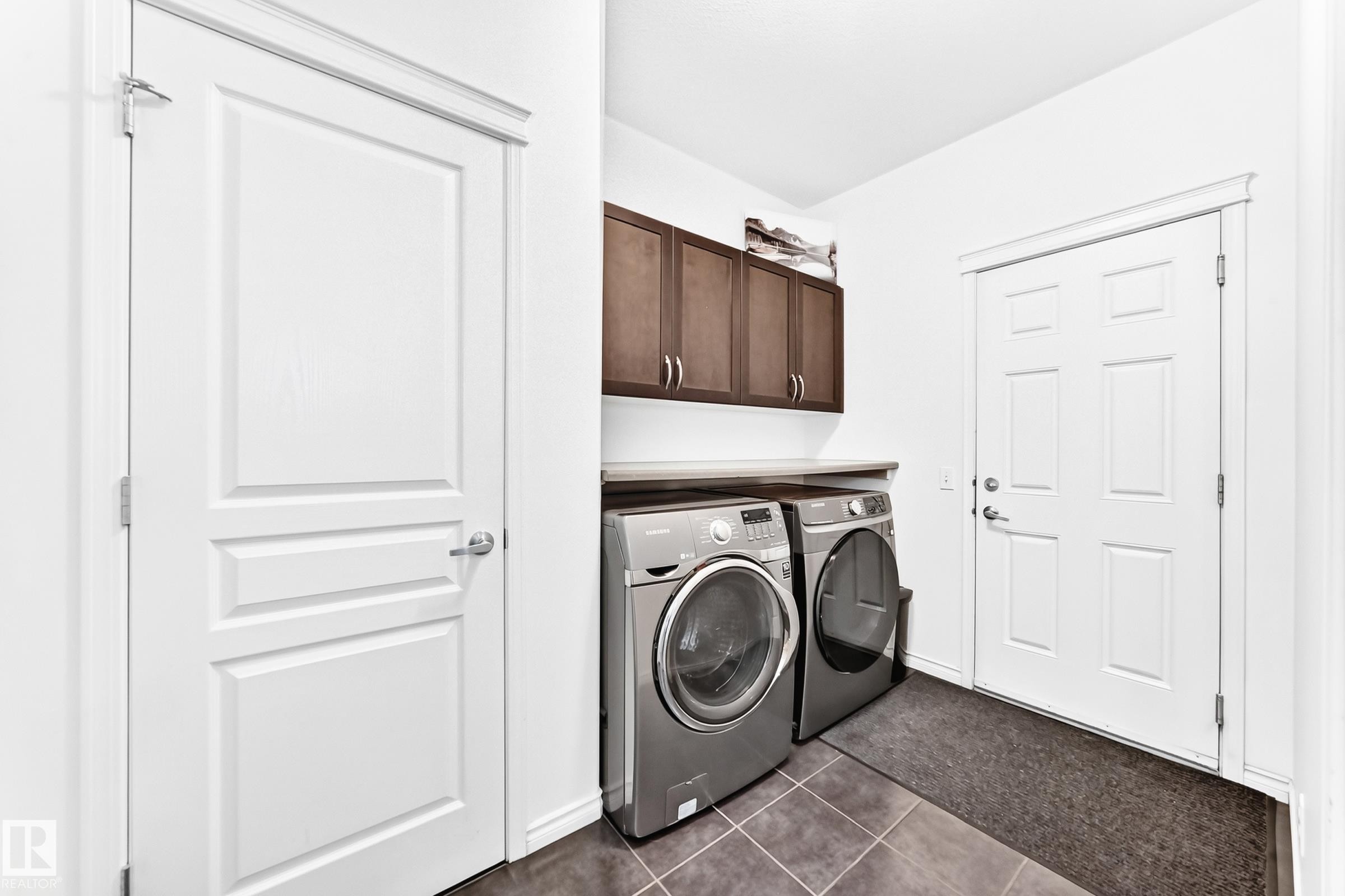 Laundry area featuring dark brown cabinetry, a light-colored countertop, and dark-toned tile flooring - 2015 Chalmers Way Sw, Edmonton, AB