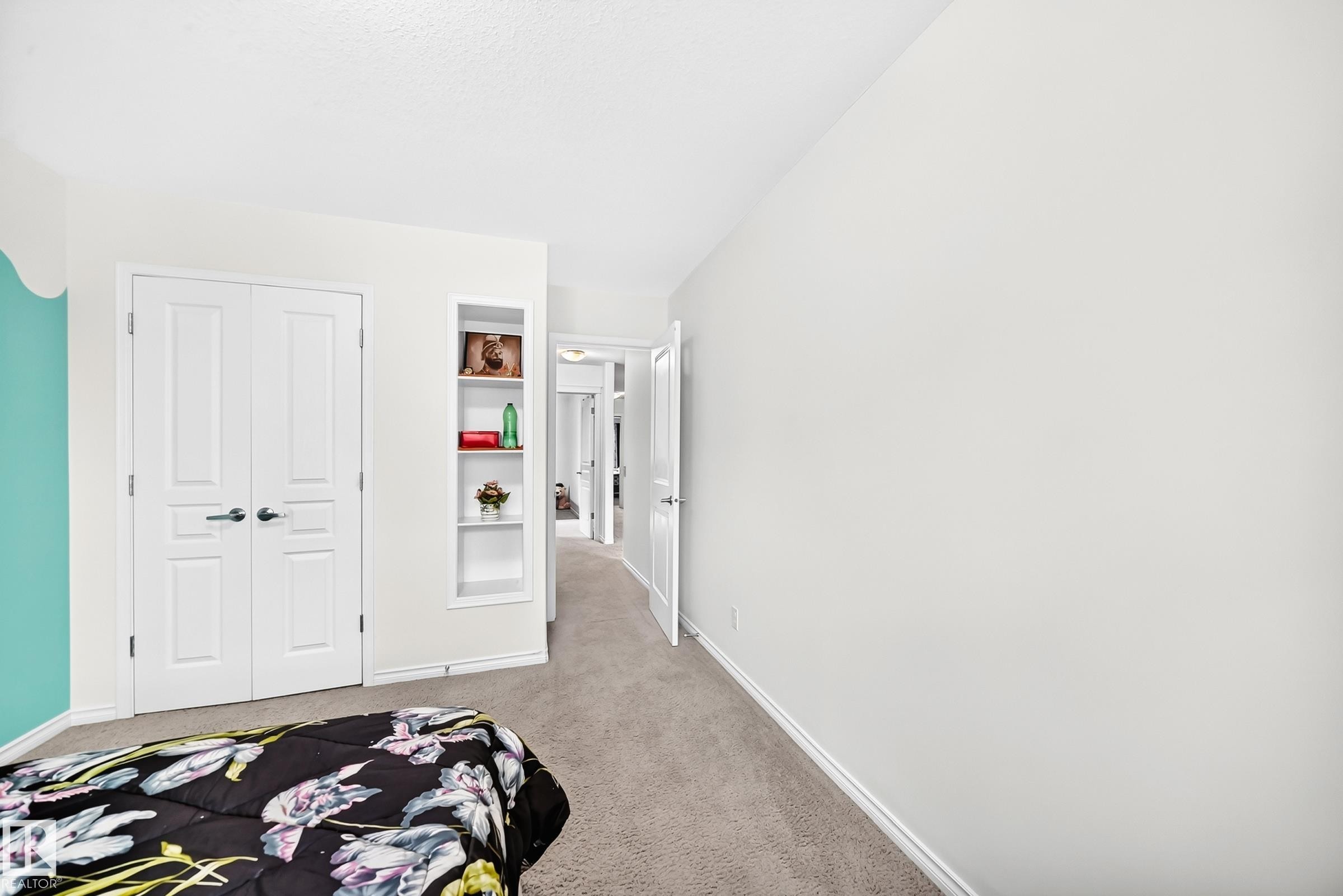 White two-panel bifold doors, built-in shelving, light gray carpeting, and a white interior door frame - 2015 Chalmers Way Sw, Edmonton, AB