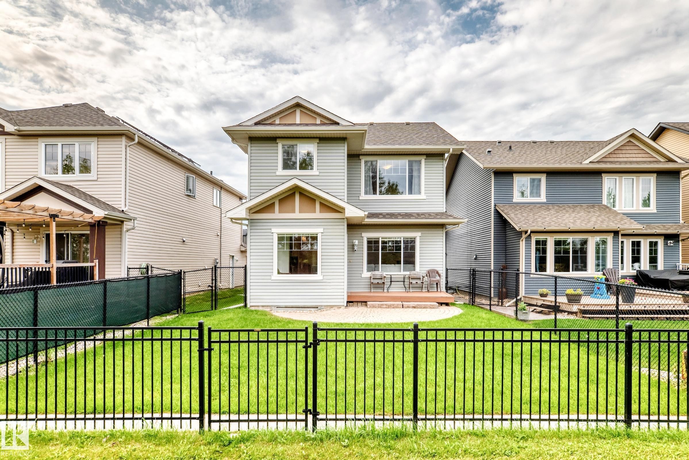Fenced backyard featuring a manicured lawn, a ground-level deck, and a paved patio area - 2015 Chalmers Way Sw, Edmonton, AB