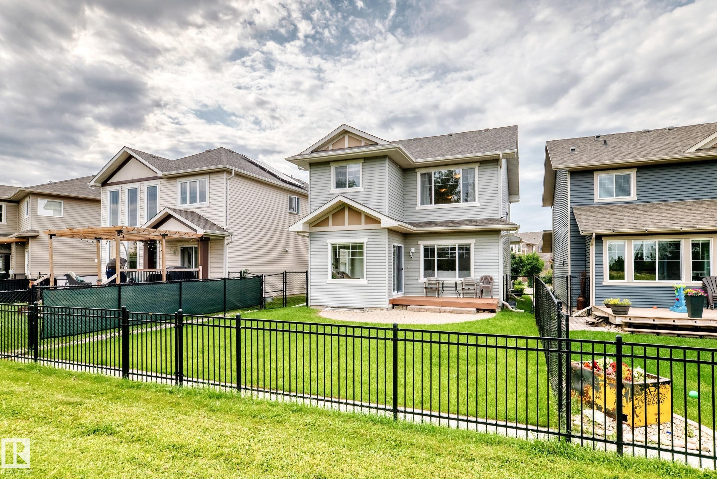Manicured lawn, black metal fencing, and a ground-level wood-finish deck - 2015 Chalmers Way Sw, Edmonton, AB