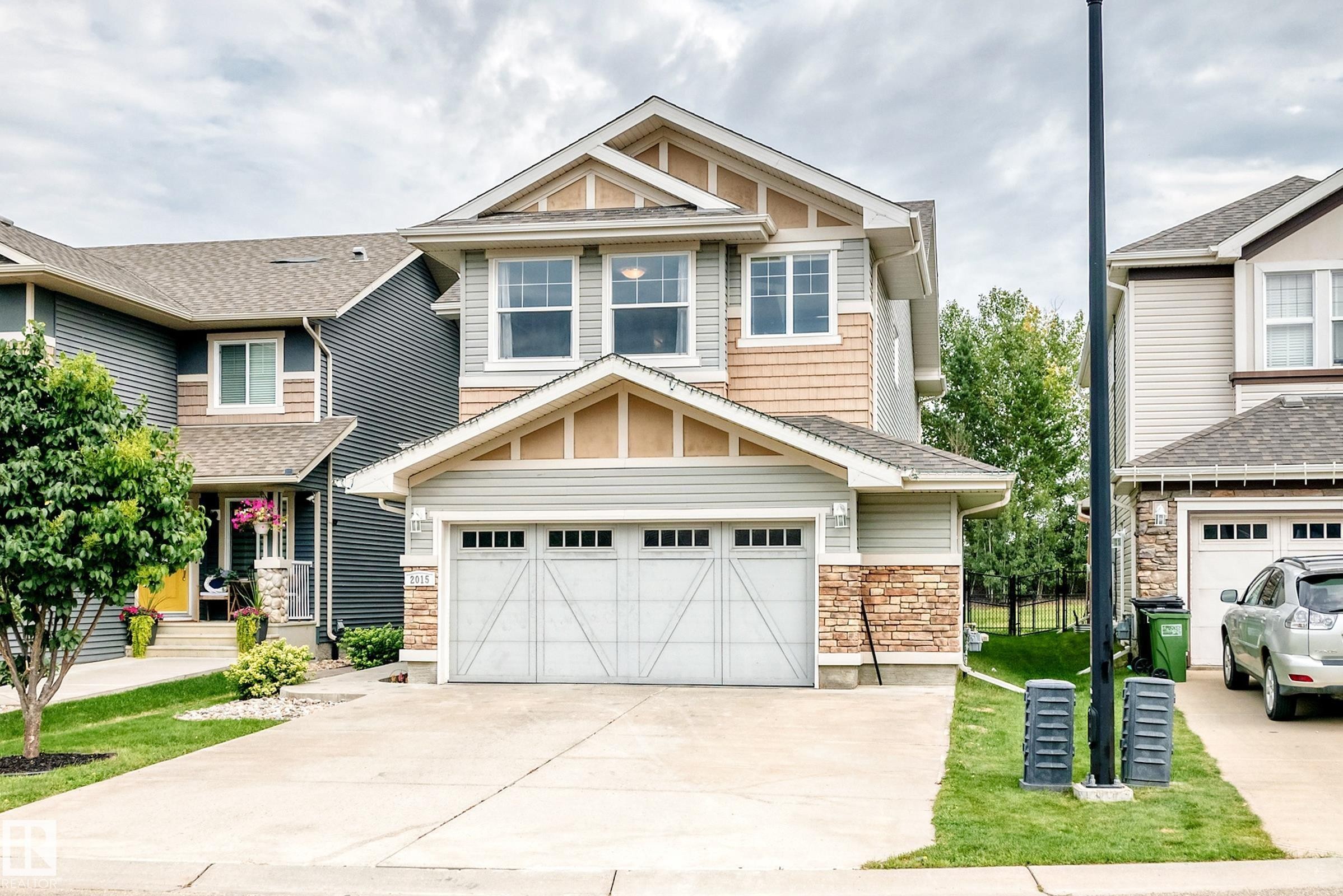 Two-story home with a two-car garage, stone accents, and a gabled roofline - 2015 Chalmers Way Sw, Edmonton, AB