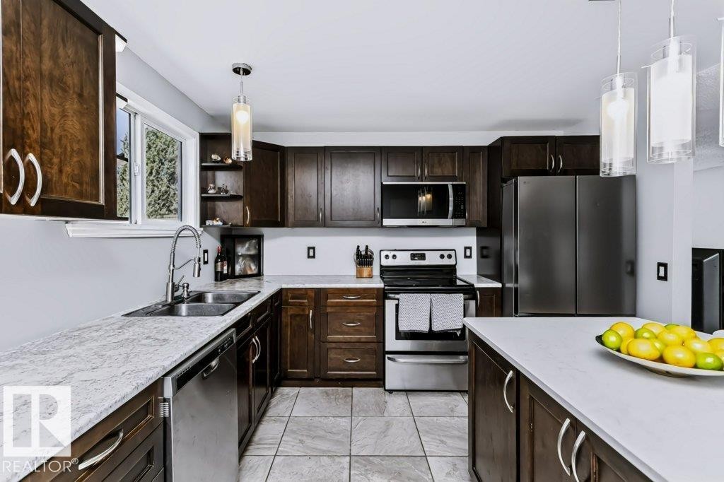 Kitchen featuring dark wood cabinetry, light-toned countertops, stainless steel appliances, and tile flooring - 18431 95A Avenue Nw, Edmonton, AB