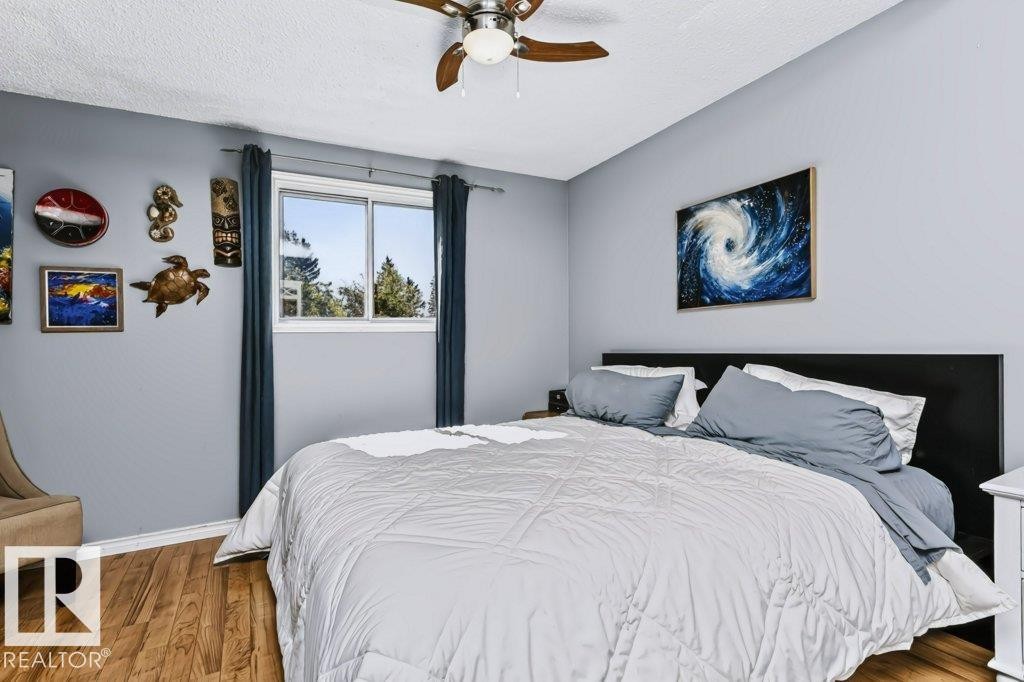 Expansive room featuring wood-finish flooring, a ceiling fan, and a large window - 18431 95A Avenue Nw, Edmonton, AB