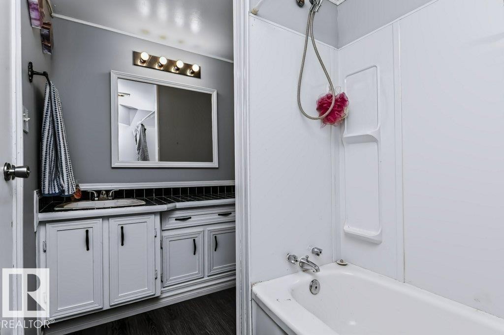White vanity with dark hardware, a single basin sink, and a framed mirror - 18431 95A Avenue Nw, Edmonton, AB