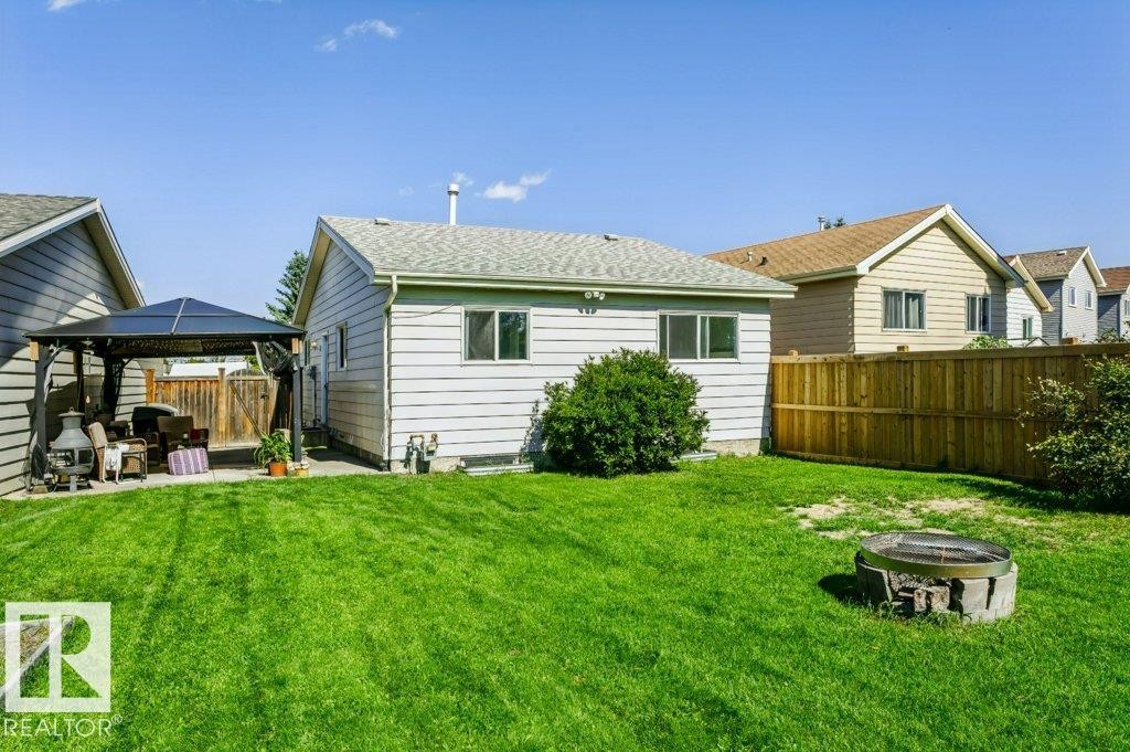 Expansive backyard featuring a concrete patio, a detached gazebo, a wood privacy fence, and a built-in fire pit area - 18431 95A Avenue Nw, Edmonton, AB