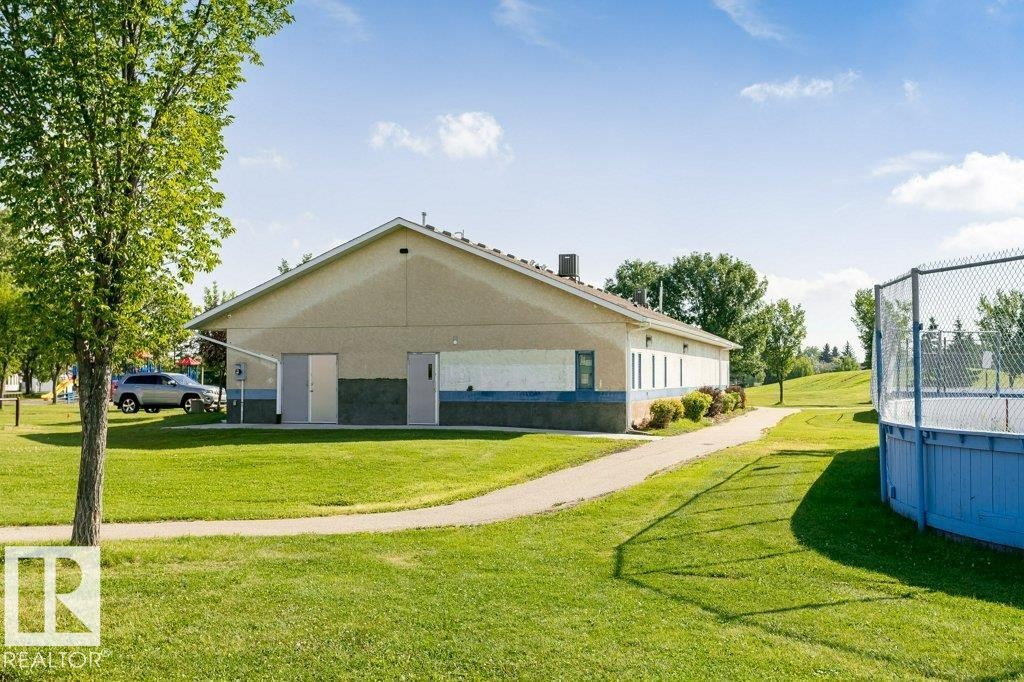 Expansive green space featuring a paved pathway, mature trees, and a recreational court with fencing - 18431 95A Avenue Nw, Edmonton, AB