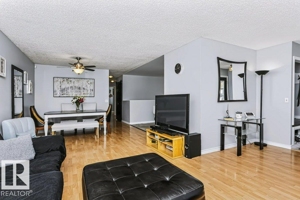 Light wood-finish flooring throughout, light gray wall tones, ceiling fan with integrated lighting, and a built-in entry nook with shelving - 18431 95A Avenue Nw, Edmonton, AB
