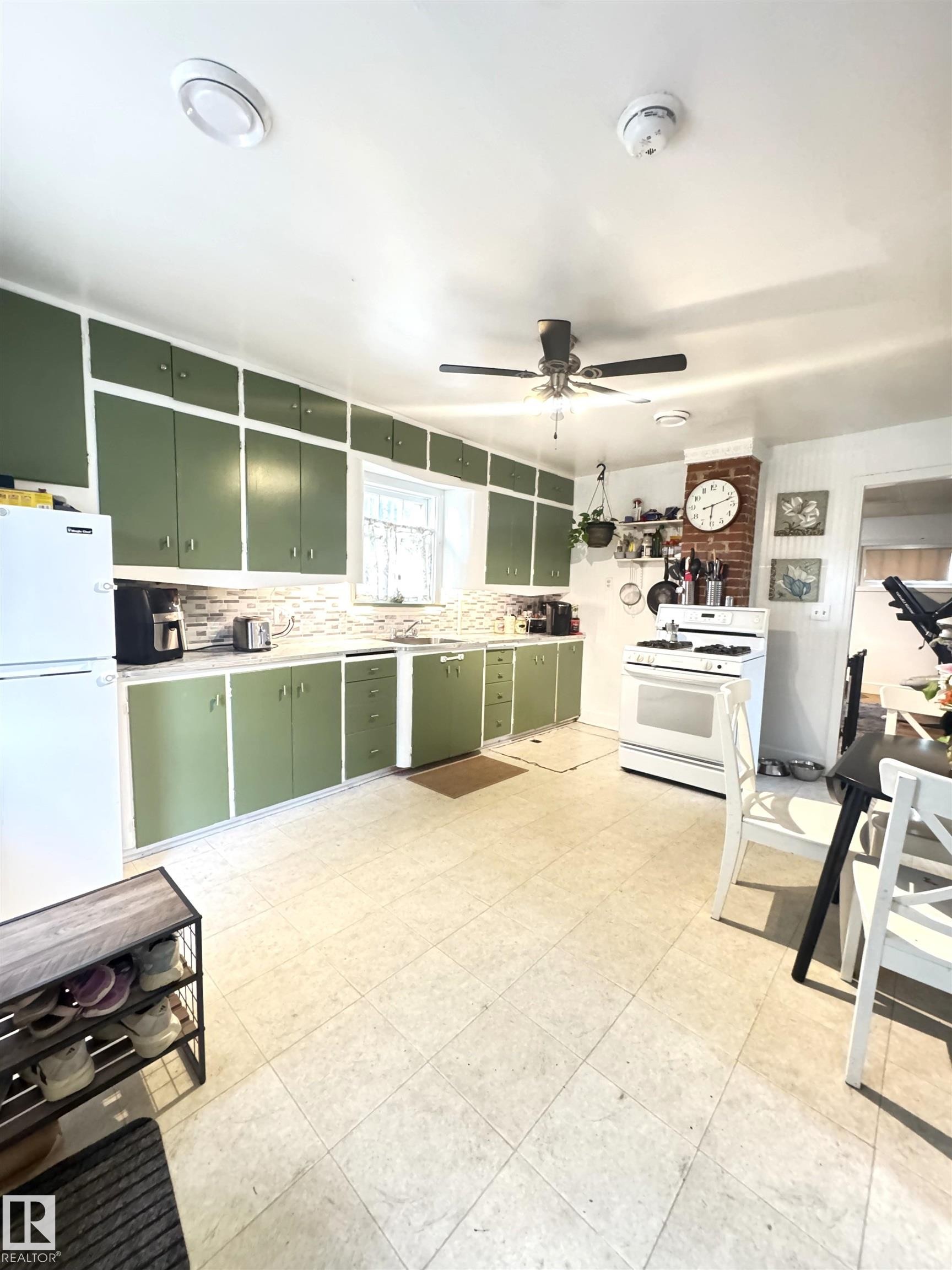 Kitchen featuring extensive green cabinetry, light-toned tiled flooring, white appliance package, and a ceiling fan - 5019 48 Avenue, Onoway, AB - Indoor Photo Showing Other Room