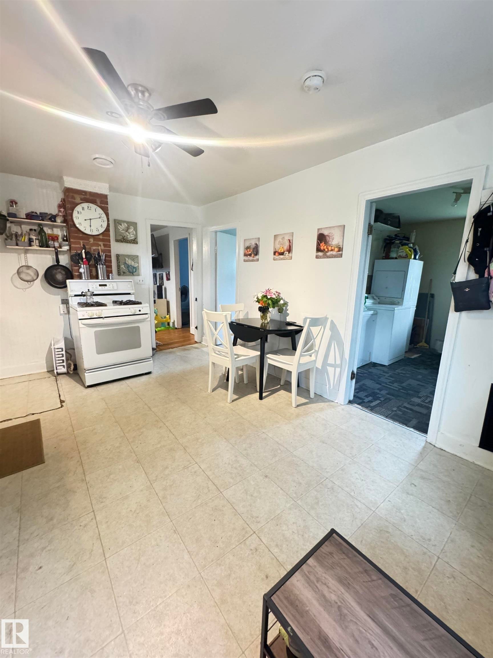 Kitchen area featuring a white gas range, tiled flooring, exposed brick accent, and a ceiling fan with integrated lighting - 5019 48 Avenue, Onoway, AB - Indoor