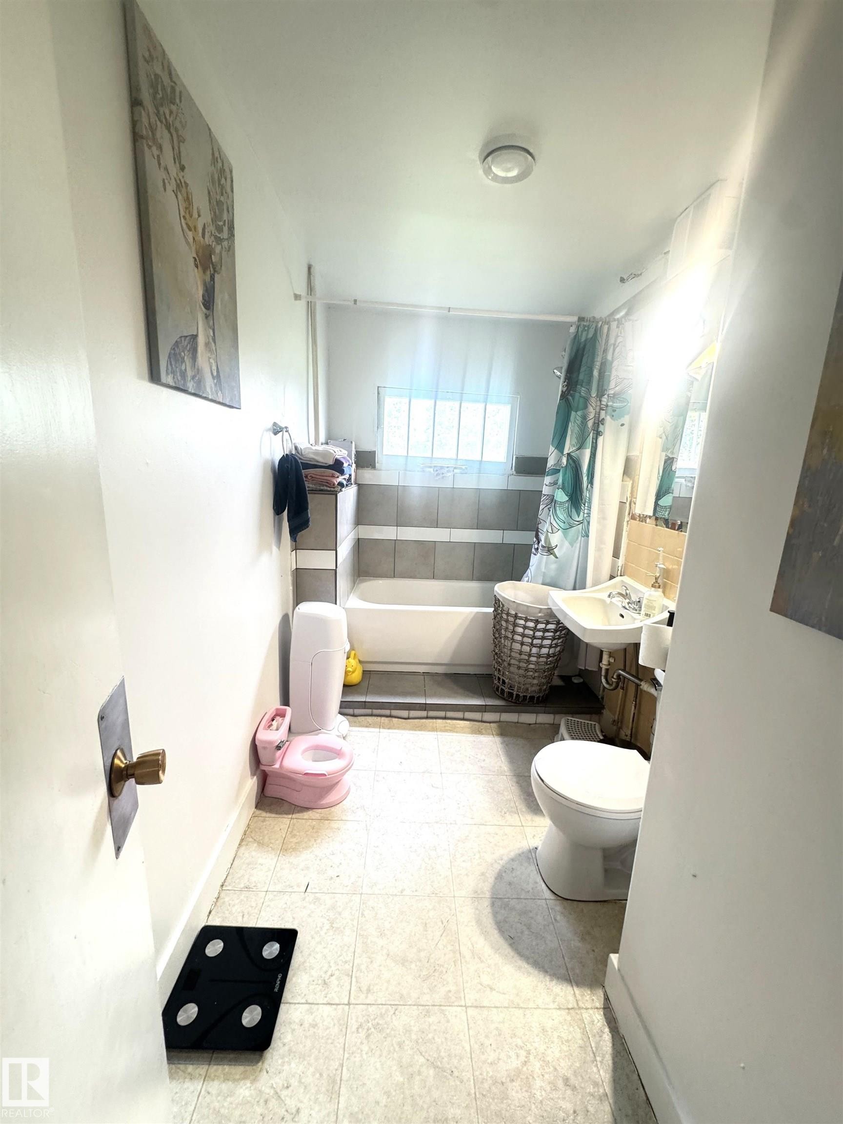 Bathroom featuring a white bathtub, ceramic wall tiling, a pedestal sink, and a toilet - 5019 48 Avenue, Onoway, AB - Indoor