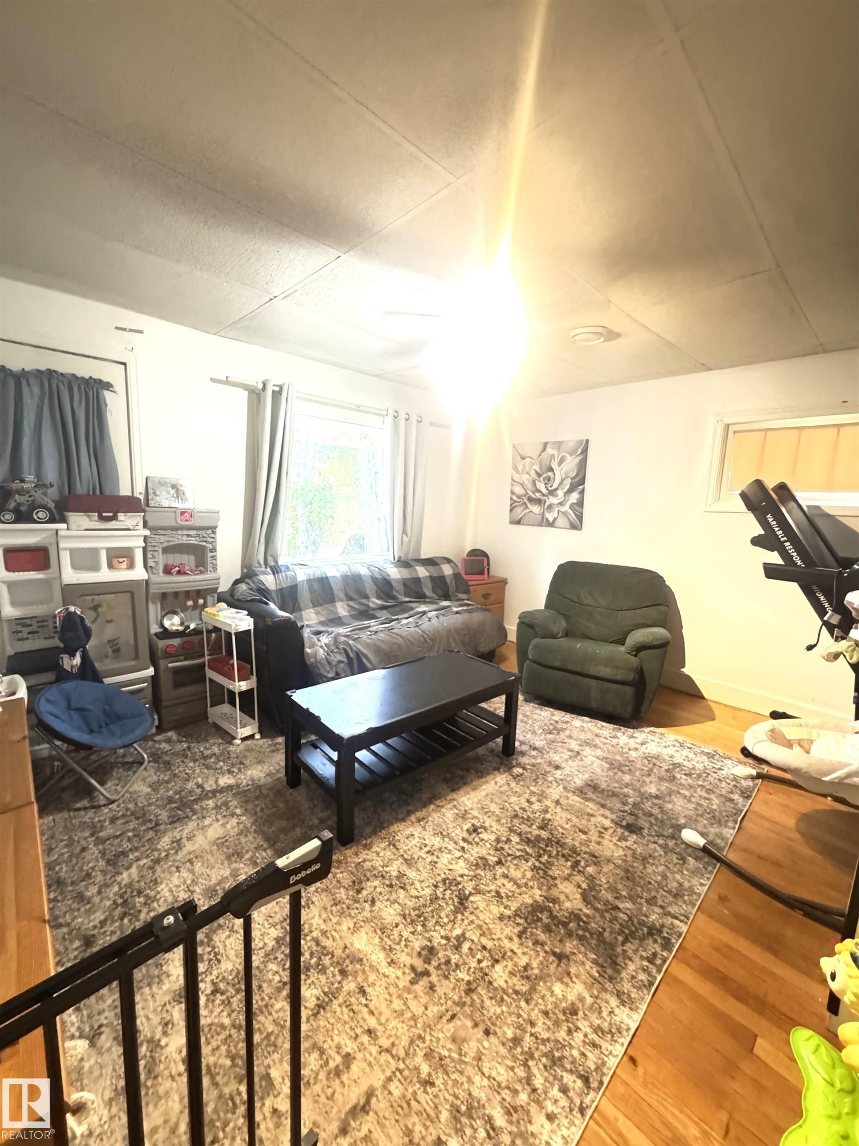 Living area featuring wood-finish flooring and a large area rug - 5019 48 Avenue, Onoway, AB - Indoor