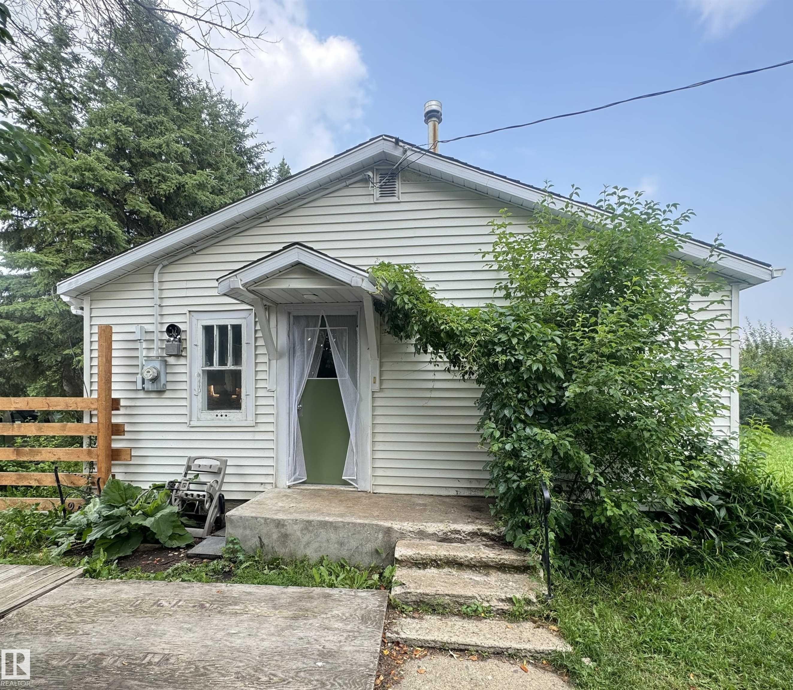 White siding exterior with a light green entry door and a covered entryway - 5019 48 Avenue, Onoway, AB - Outdoor