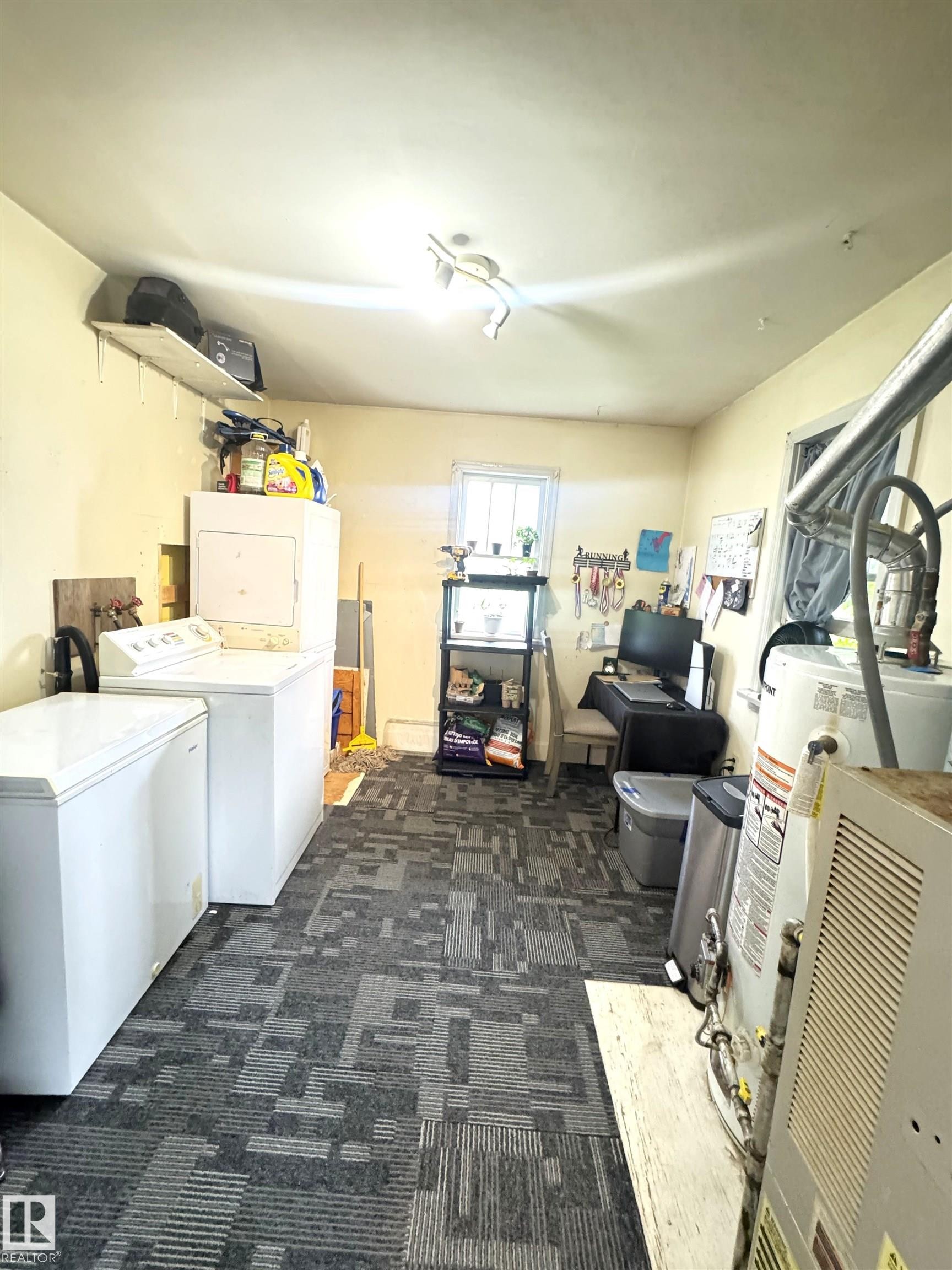 Utility space with patterned carpet flooring, a single window, track lighting, and a wall-mounted shelf - 5019 48 Avenue, Onoway, AB - Indoor Photo Showing Laundry Room