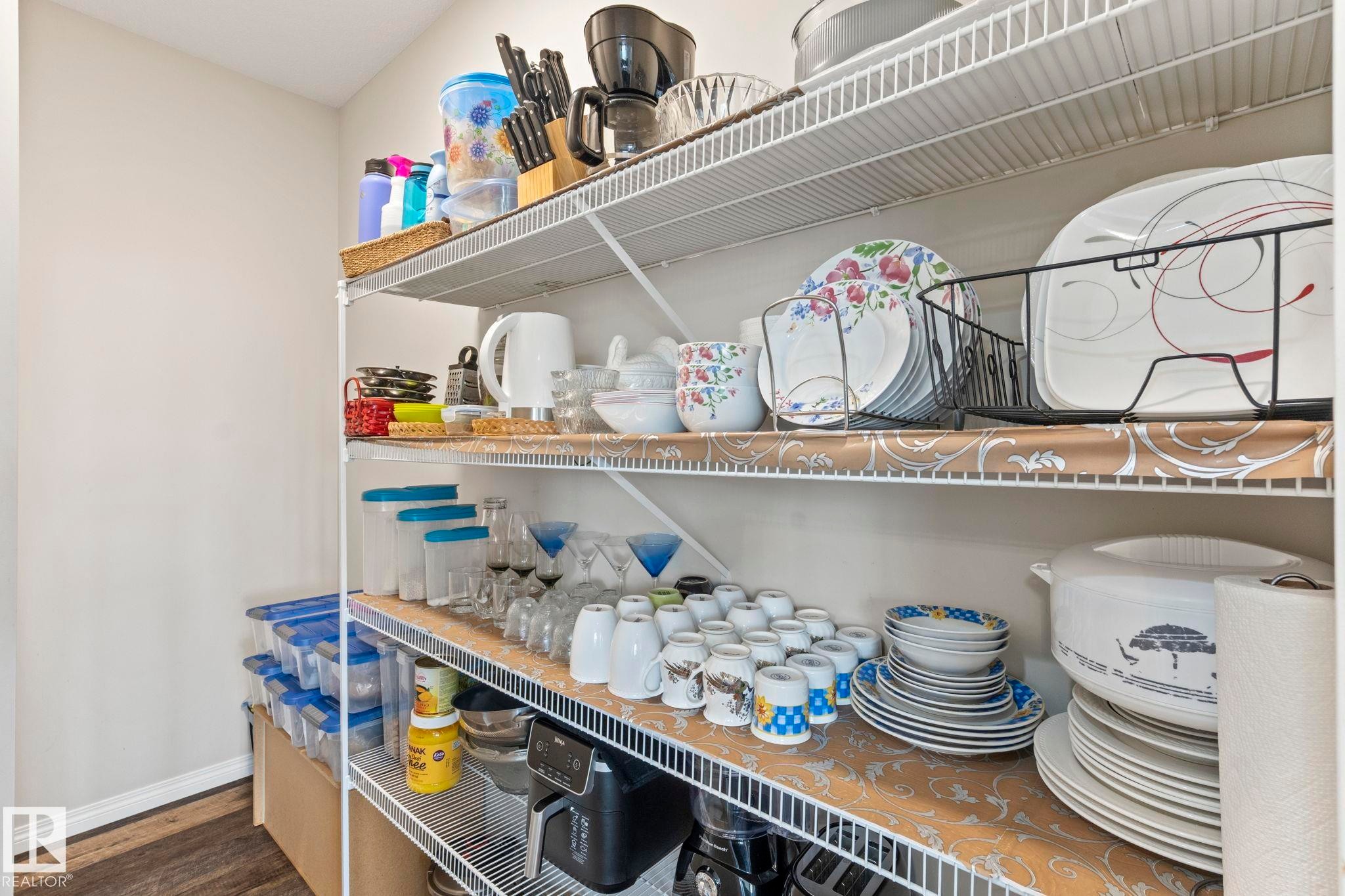 Pantry featuring white wire shelving, light neutral wall paint, and wood-finish flooring - 2131 51 Sw, Edmonton, AB - Indoor