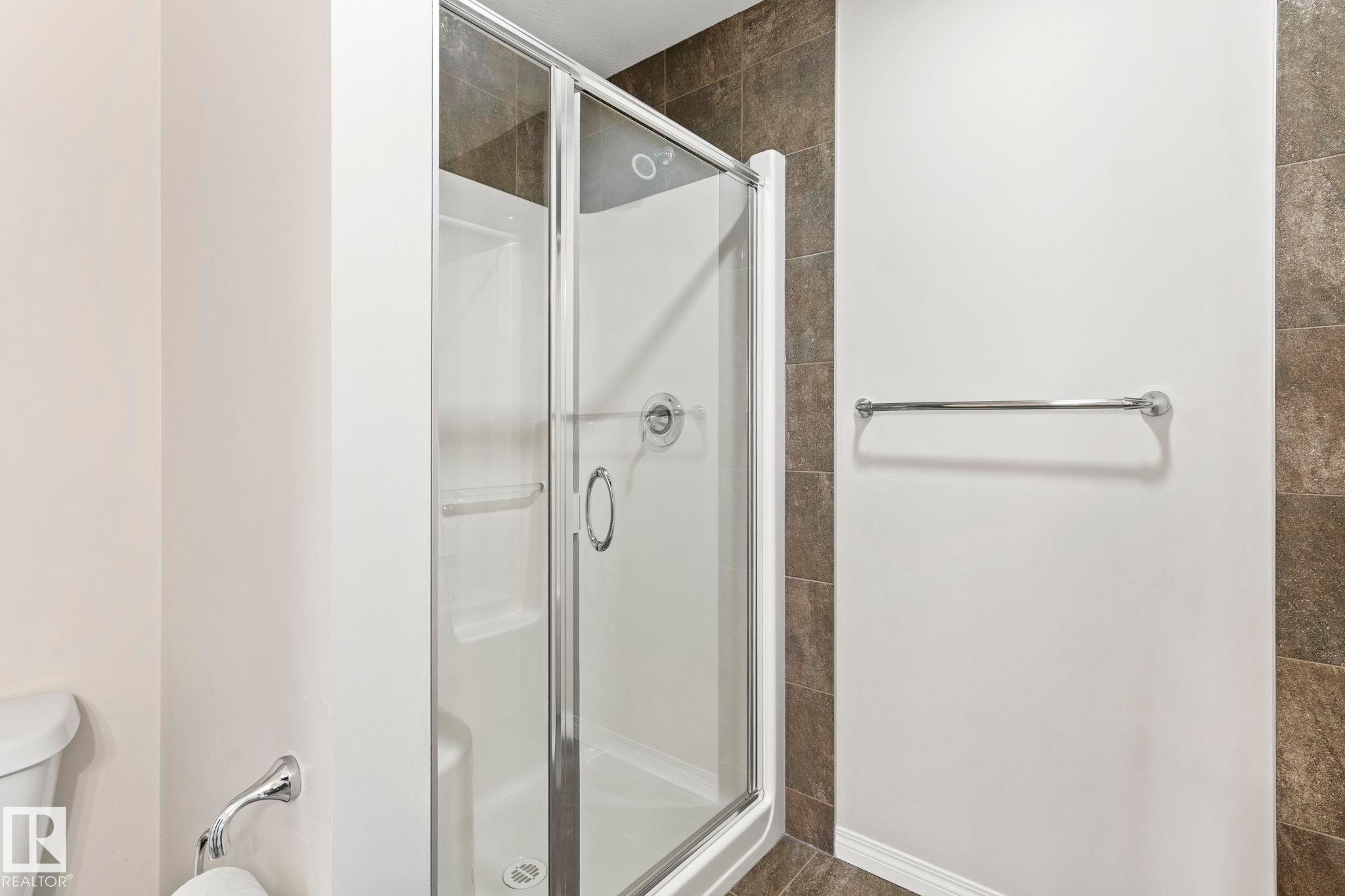 Glass-enclosed shower stall with a white base and silver-toned hardware - 2131 51 Sw, Edmonton, AB - Indoor Photo Showing Bathroom